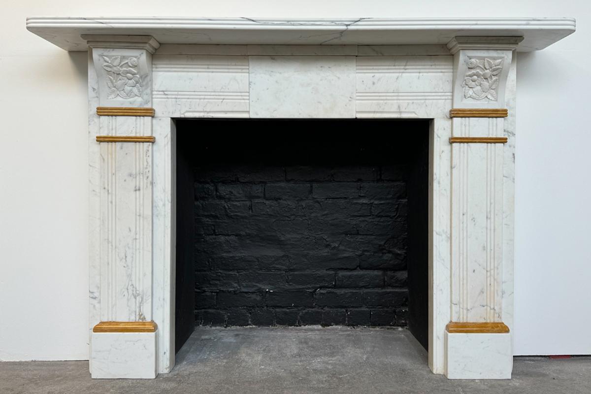 Antique Victorian statuary white marble fire surround. The reeded jambs are decorated with sienna marble interruptions and terminate in book matched floral carved corbels. Further reeding to the frieze flanks a plain central tablet. The whole sits