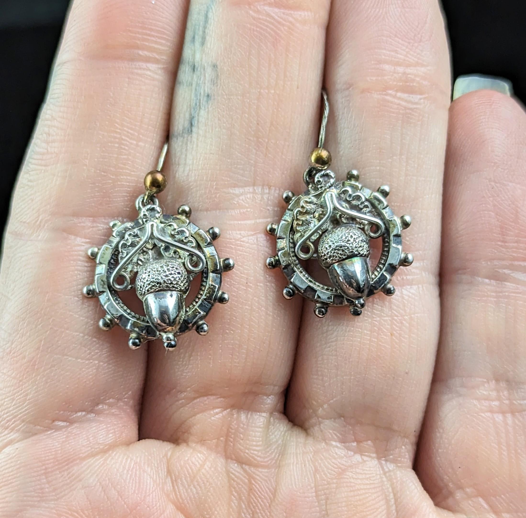 A gorgeous pair of antique Victorian silver acorn earrings.

They are circular shaped earrings with a beaded outer border and an oak leaf and acorn to the centre.

Acorns were a very popular motif in Victorian jewellery and are highly sought after