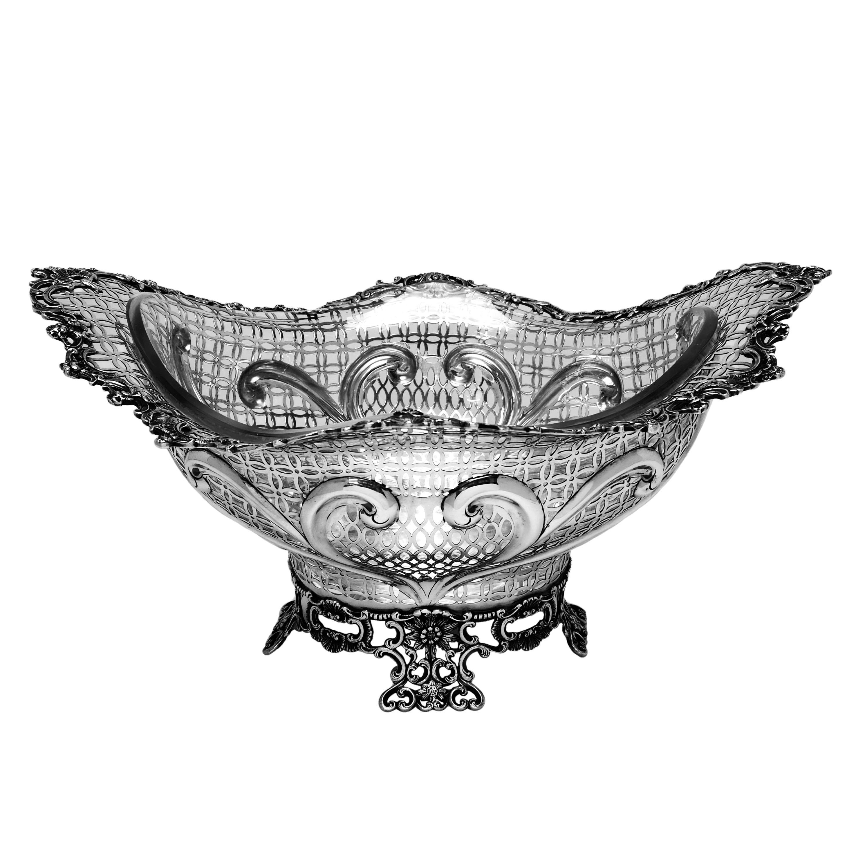 Un magnifique panier en argent massif de style victorien antique avec une doublure en verre transparent. Ce panier est de taille importante et présente des motifs complexes percés et ciselés. Le bord et le pied de la coupe présentent un motif floral