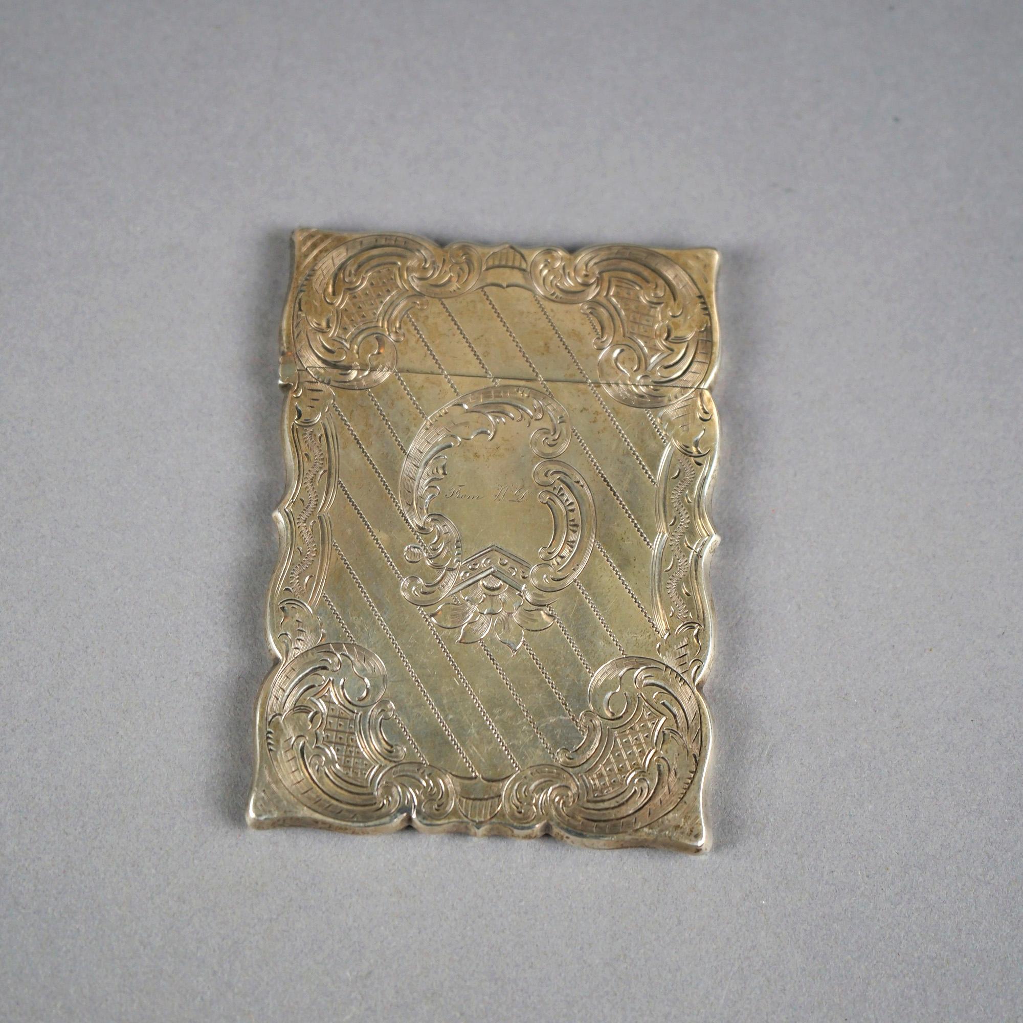 An antique Victorian calling card case offers sterling silver construction with foliate and scroll elements, engraved 
