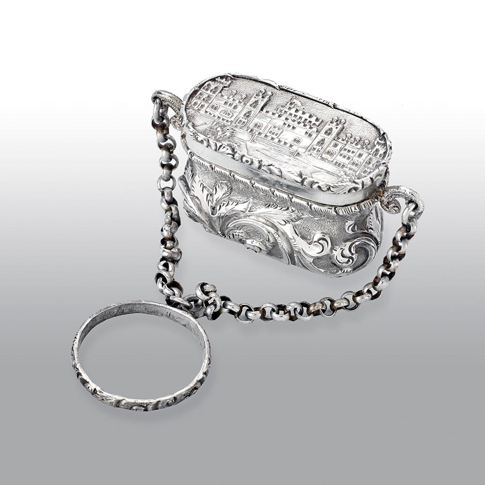 A fine antique Victorian silver castle-top vinaigrette, has a waisted bag form, chased foliate scroll decoration on a matted background, the hinged cover with a view of the castle with the round tower, the fine silver gilt interior with a pierced