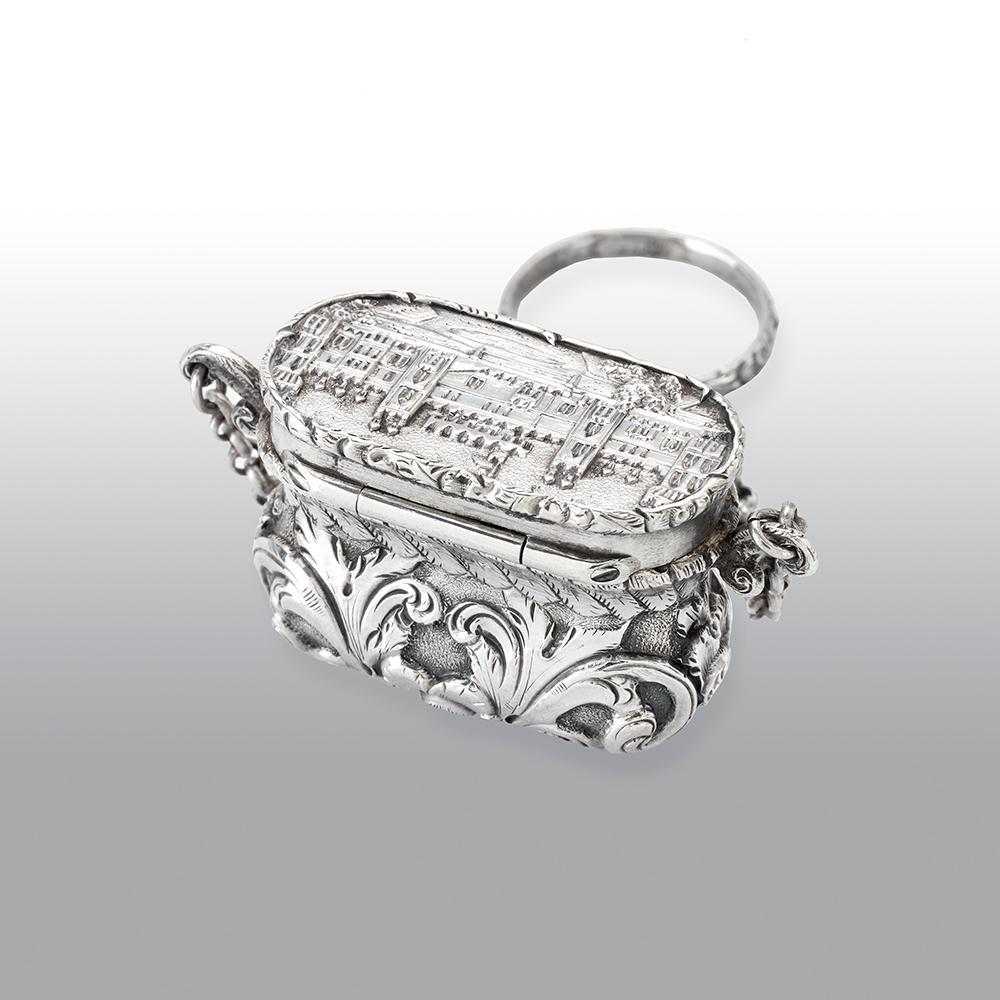 A fine antique Victorian silver Castle-top vinaigrette, has a waisted bag form, chased foliate scroll decoration on a matted background, the hinged cover with a view of the castle with the round tower, the fine silver gilt interior with a pierced