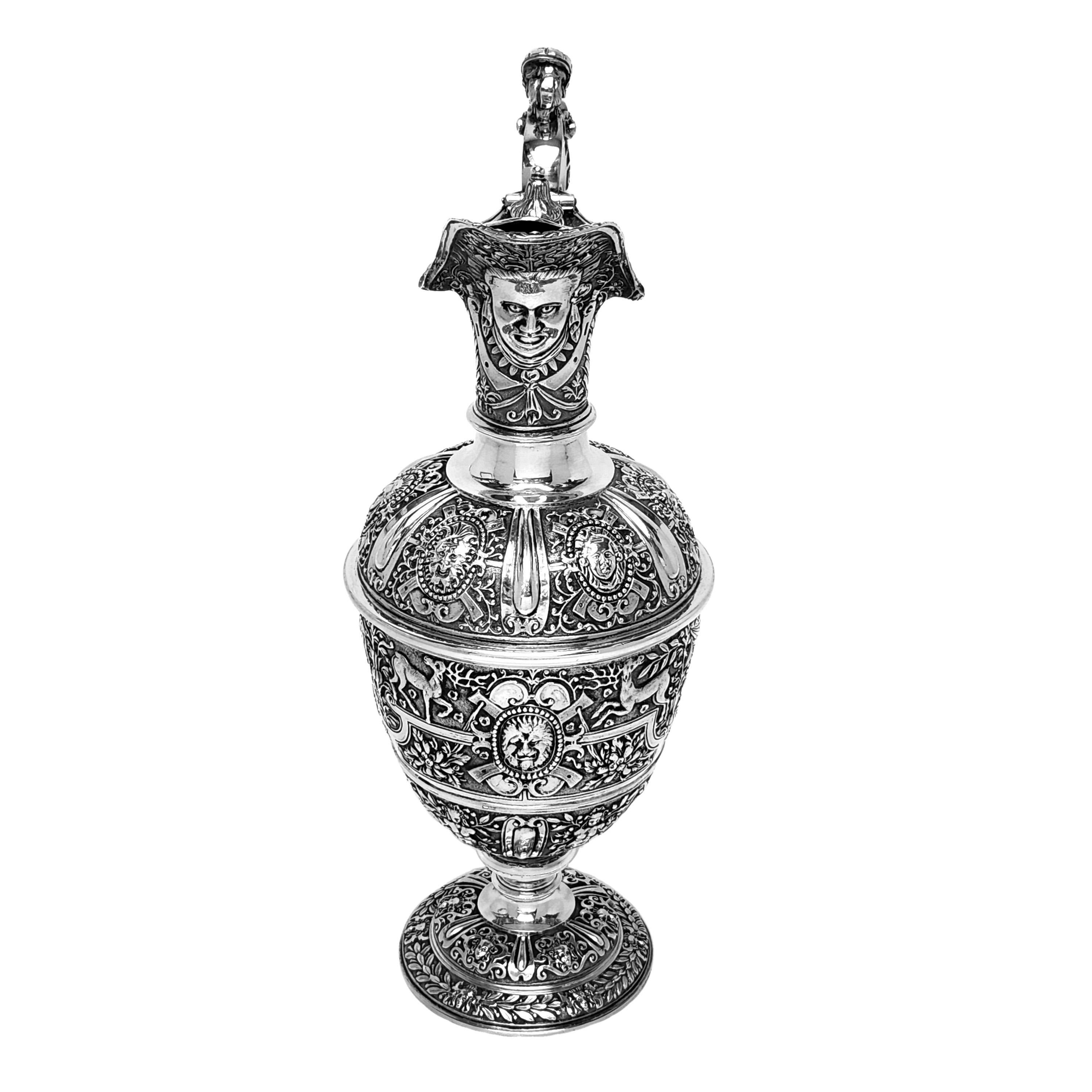 A beautiful Classic Antique Victorian solid Silver Jug in the traditional 'Cellini' design. The Jug features rich, detailed chased patterning and a figural handle and thumb piece. The chased imagery shows classical faces, assorted animals including
