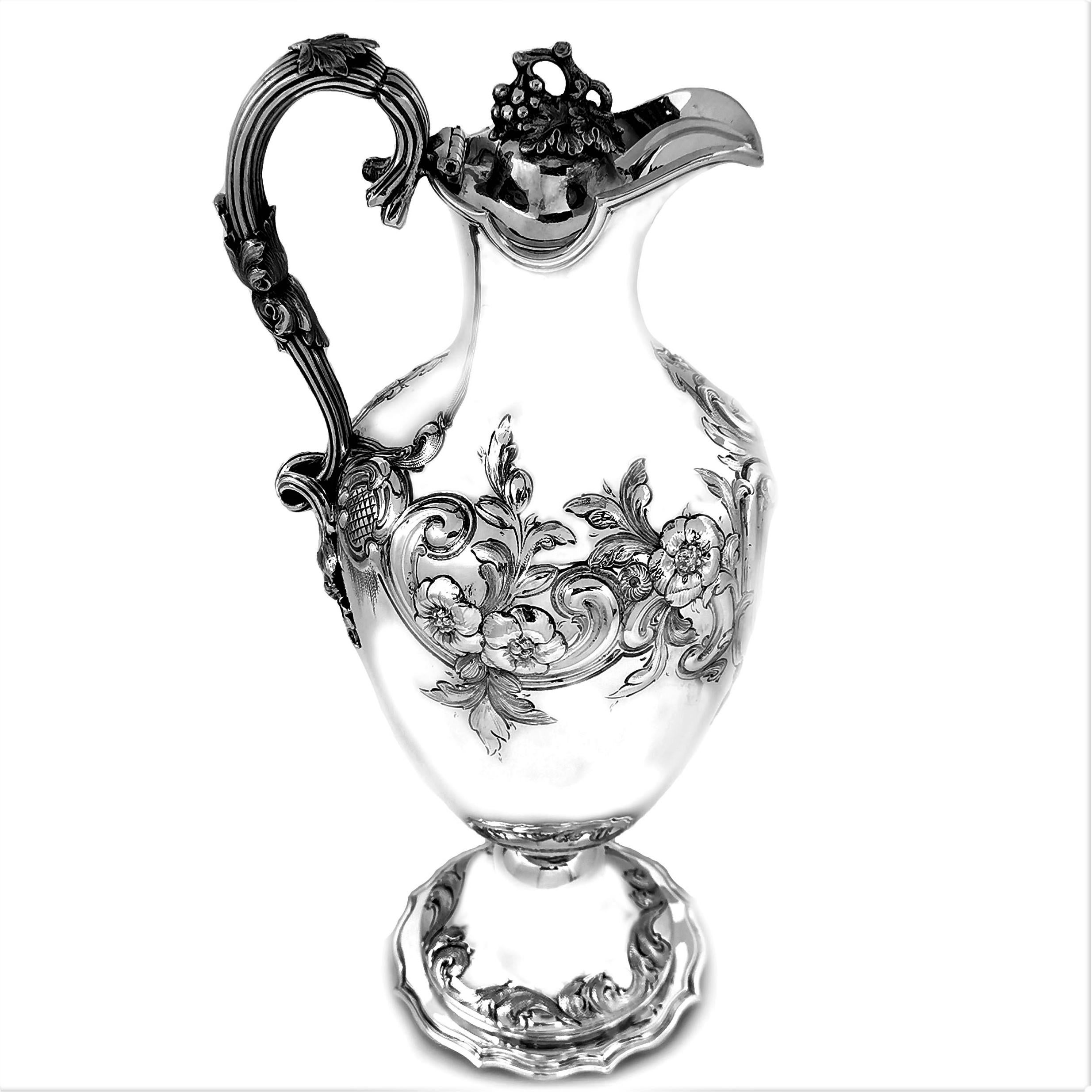 An elegant Antique Victorian solid Silver Wine / Claret Jug decorated with a beautiful chased floral and scroll design on either side of a scroll bordered cartouche. The Jug has a fine reeded handle embellished with a leaf and grape design in the