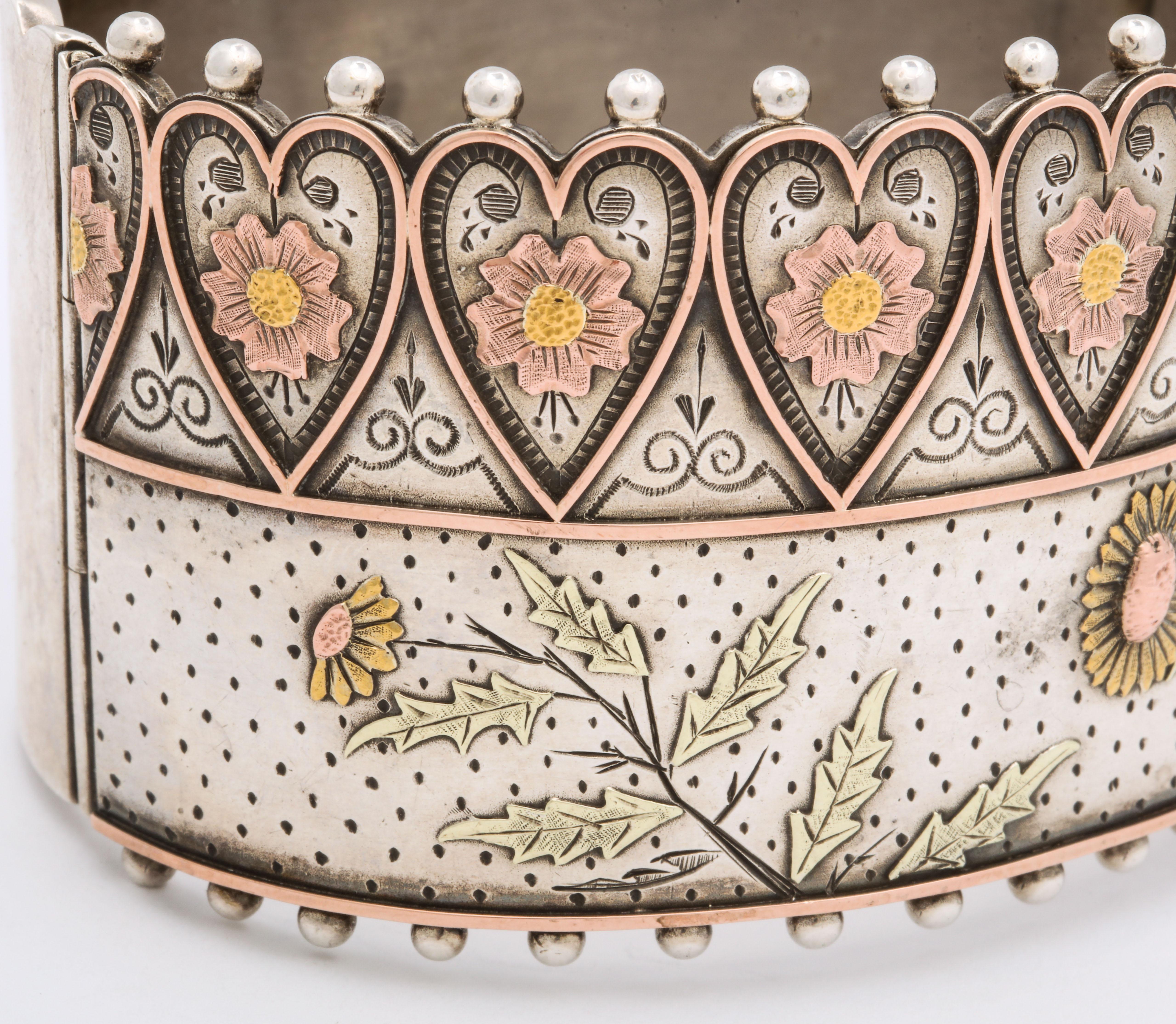 A rare design English Cuff Bracelet reaches the heights with hearts, daisies, gold, sterling and fine condition. The entire front is engraved with daisies inside the hearts and below the gold central dividing line. The symbolism of the Victorian era