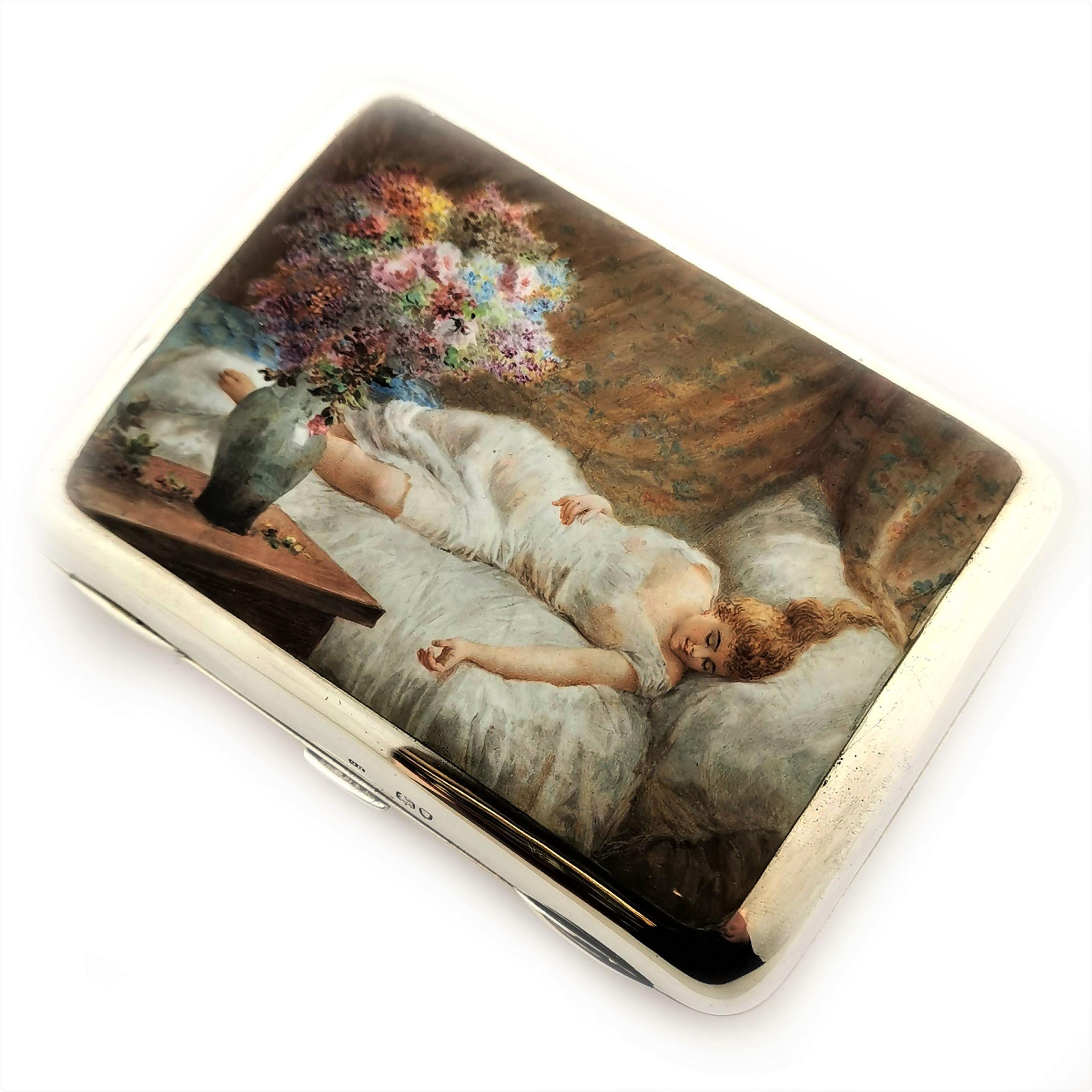 An antique solid Silver Cigar Case with a gorgeous enamel image on the front cover. This image shows a woman in a sheer nightdress reclining on a bed. There are flowers in the fore ground and ornate fabric in the background. This image is rendered