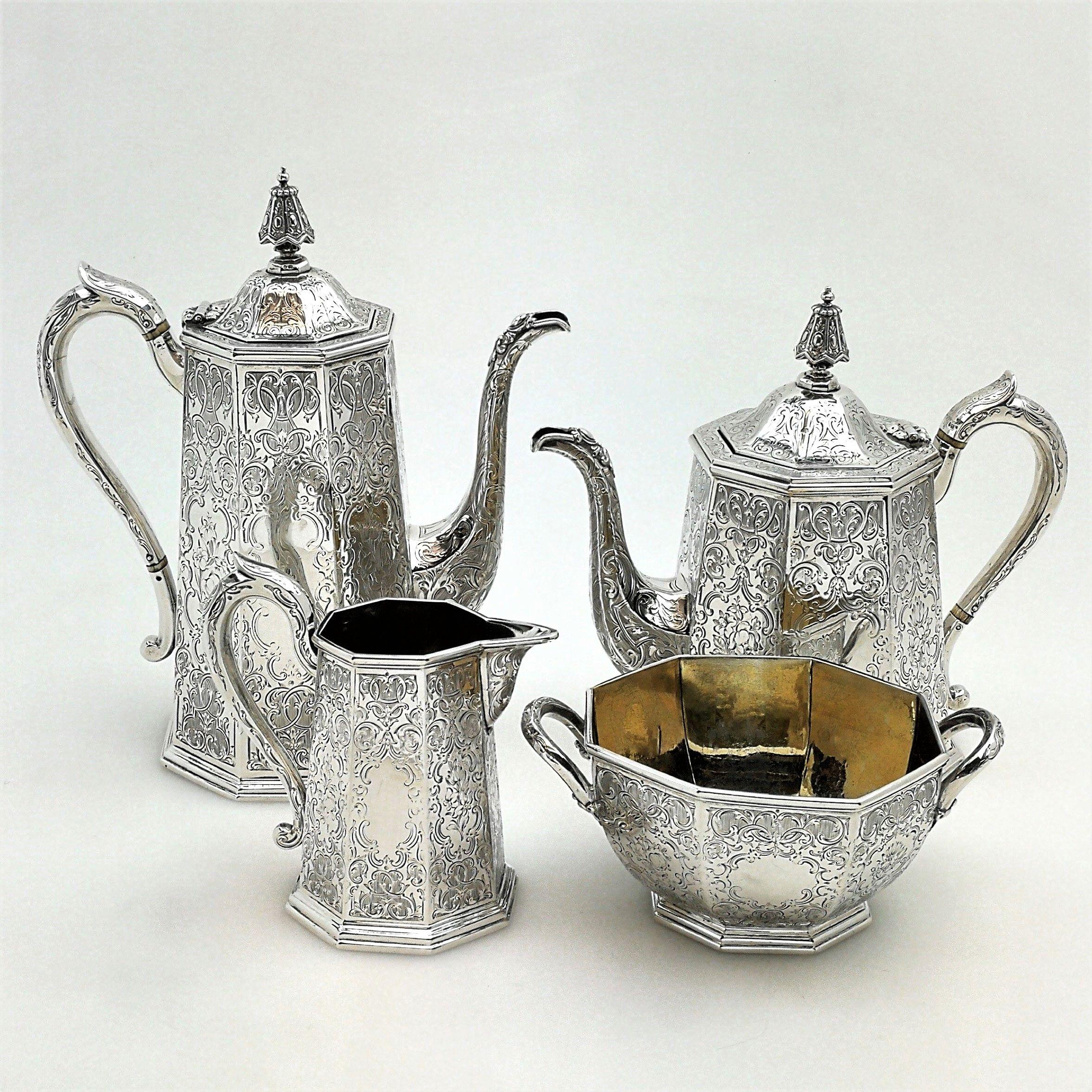 A gorgeous antique Victorian solid silver 4-piece tea set in a slightly tapered octagonal shape. The exterior of each piece is embellished with beautiful ornate engraved designs of floral and scroll patterning. Two opposite panels on each piece have
