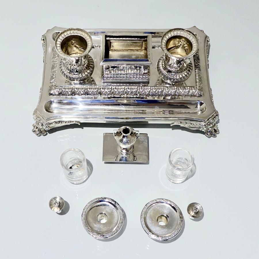 A splendid rectangular Victorian inkstand decorated with an inner ornate galleried border and two elongated oval pen trays. The ornate drum inkwells have a lower gadroon border for lowlights and the inkstand itself sits on four decorative claw