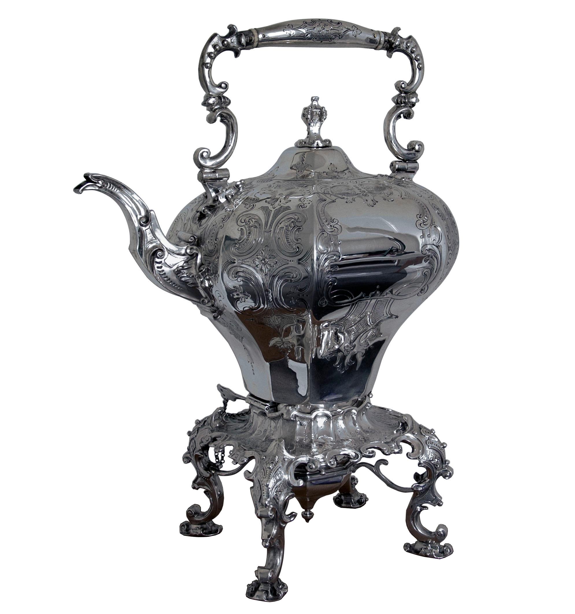 A large decorative Victorian silver kettle on lamp stand. The octagonal kettle standing on a decorative stand supported by four cast legs of scrolling form. The body of the kettle decorated with engraved design and having a decorative cast spout and