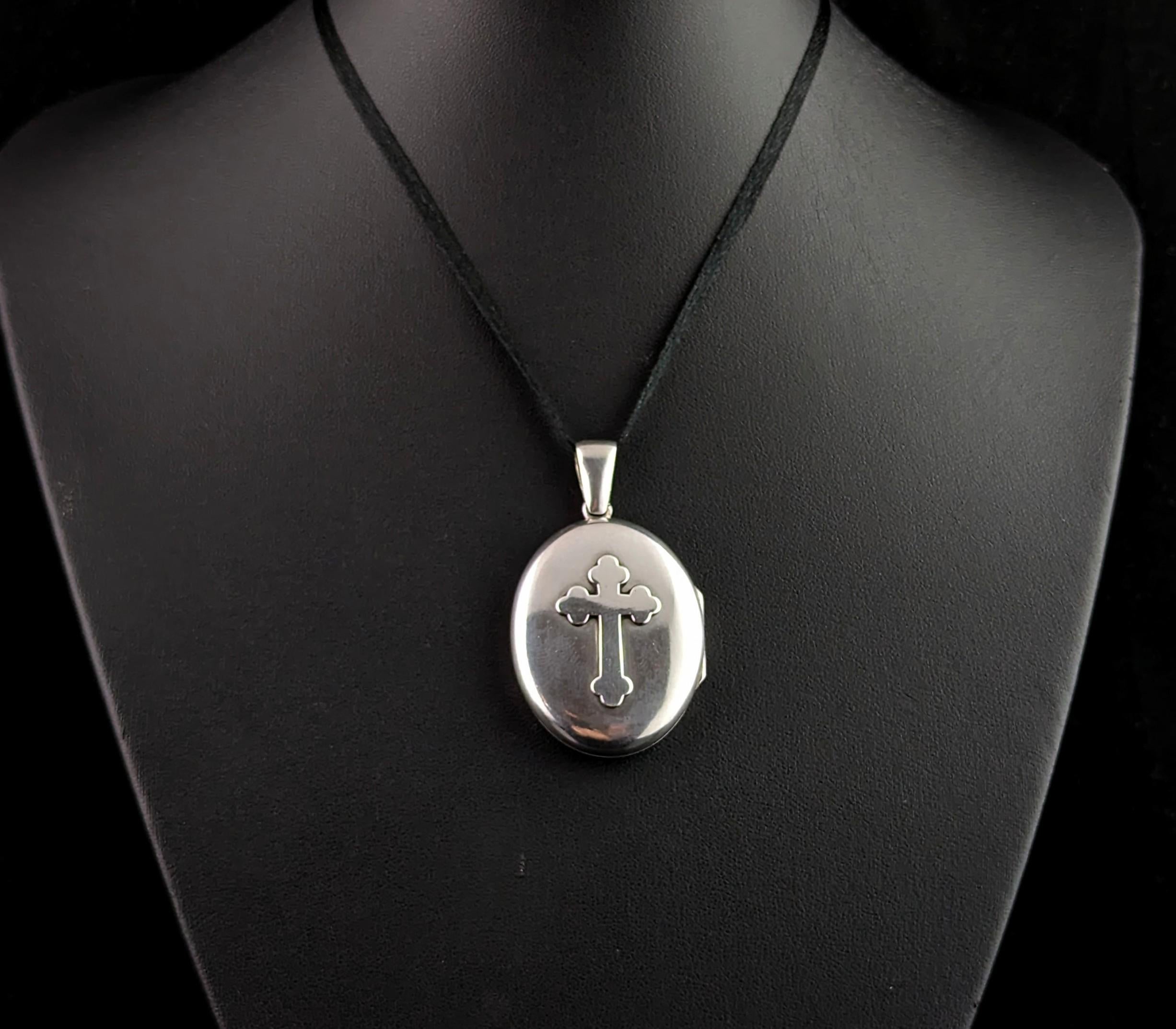 This antique Victorian sterling silver locket is truly unique and incredibly beautiful.

This locket is an oval shaped locket with smooth polished sides, one side has cross design in a low relief design and the other has an engraved monogram in