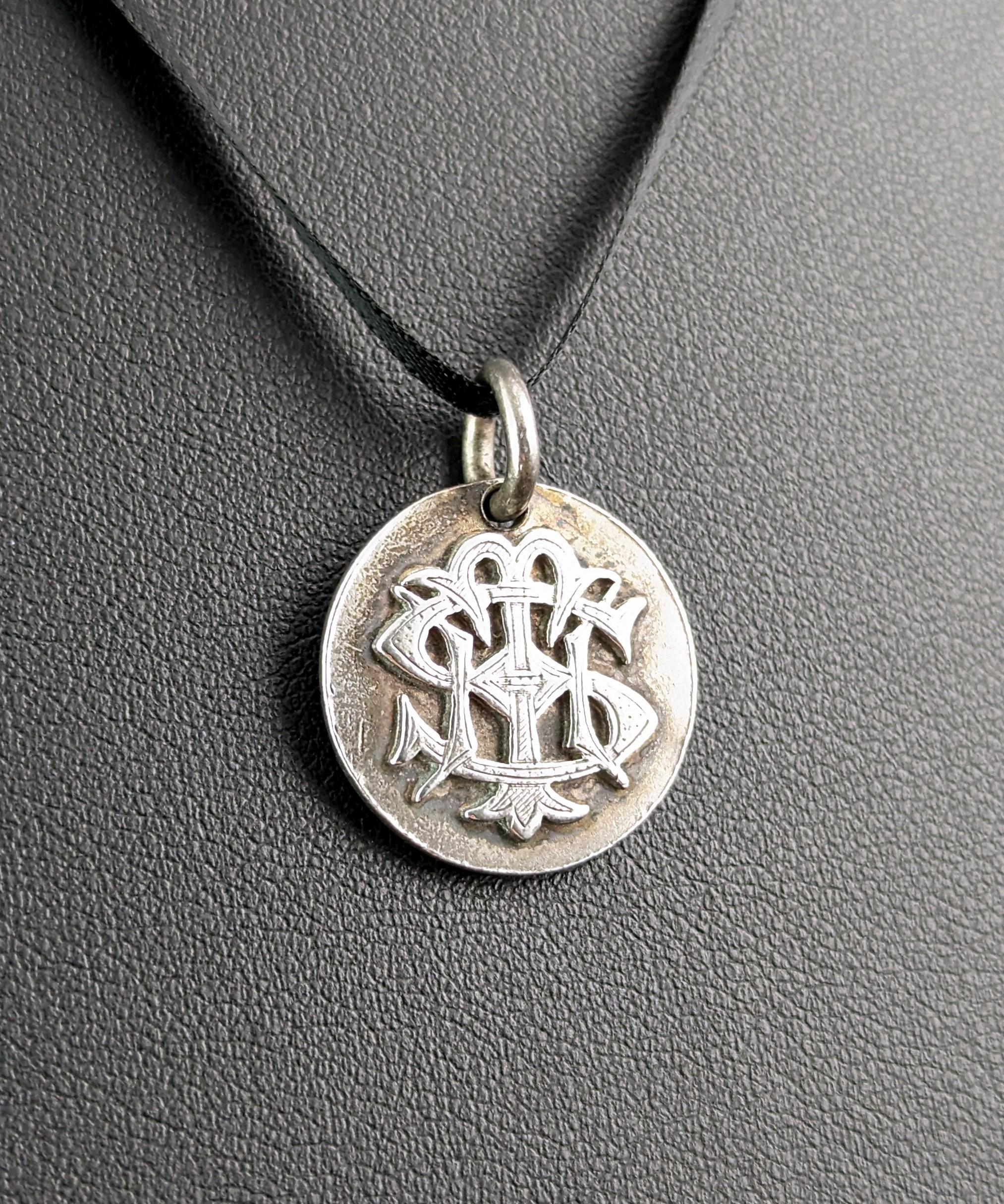 This antique Victorian era monogram pendant is interesting and unique.

Possibly adapted from a coin it has two different monograms on each side, raised in relief in gothic script.

One side reads CMB or any combination and the other THS.

This
