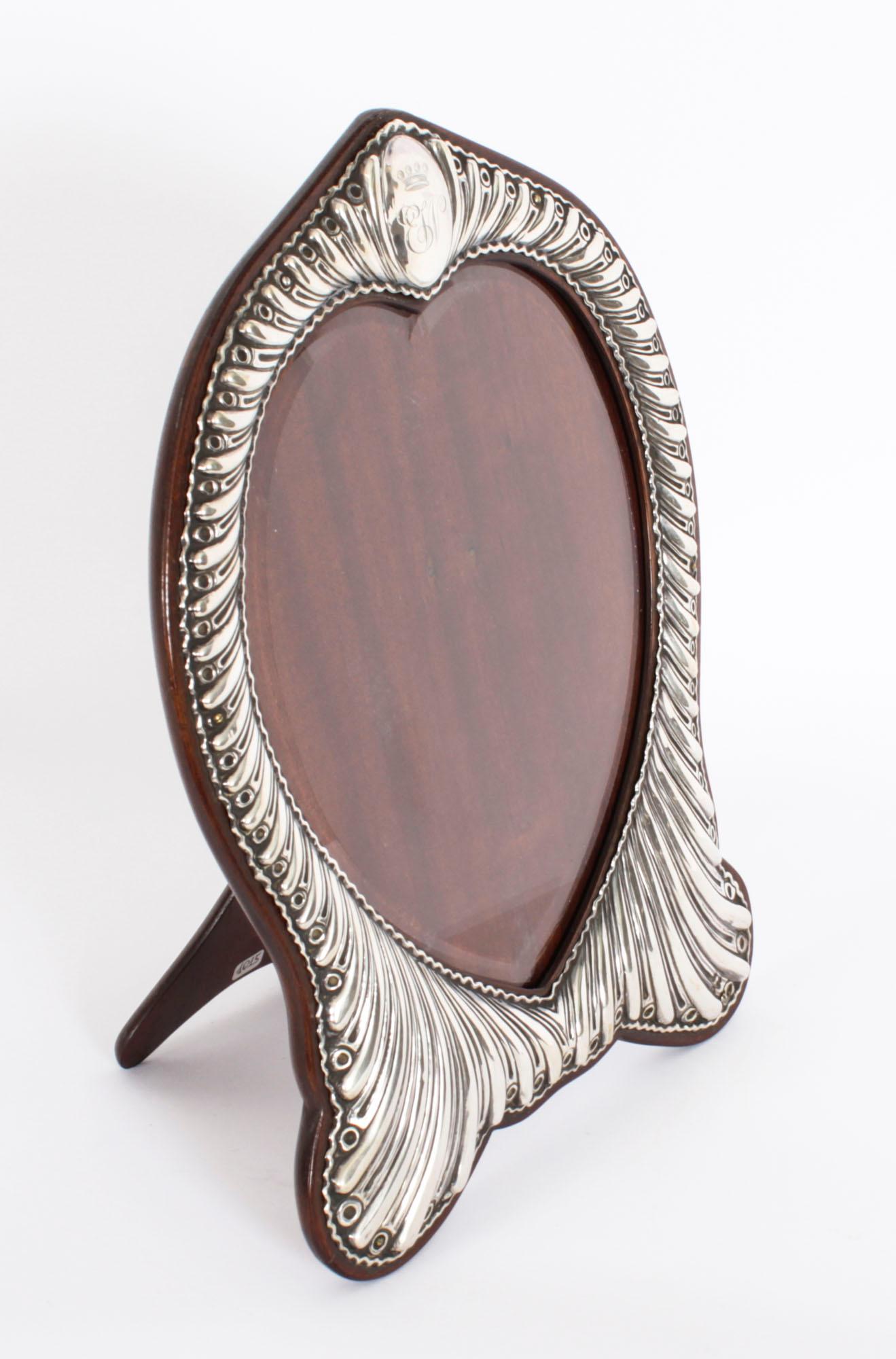 A superb Victorian sterling silver photograph frame by William Comyns, wuth hallmarks for  London 1894.

A beautiful portrait  frame decorated with a decorative heart shaped aperture and a fluted border, with a cartouche and a polished  oak easel