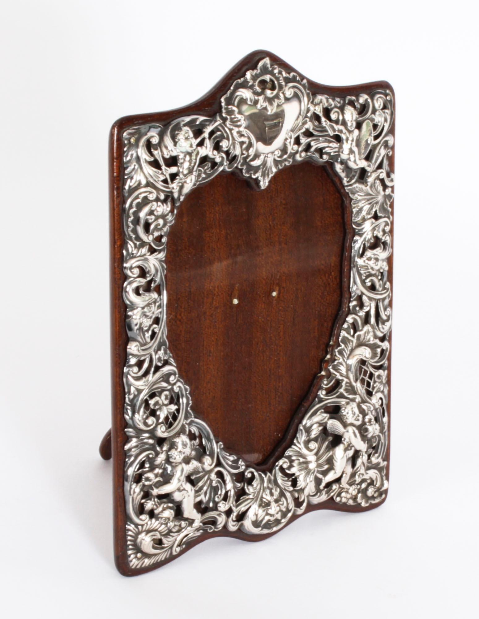 Soberbio marco de fotografía victoriano antiguo de plata esterlina, con marcas del prestigioso platero William Comyns y sellos de Londres de 1897.

Hermoso marco de retrato decorado con decoración calada y repujada de gusto rococó con putti,