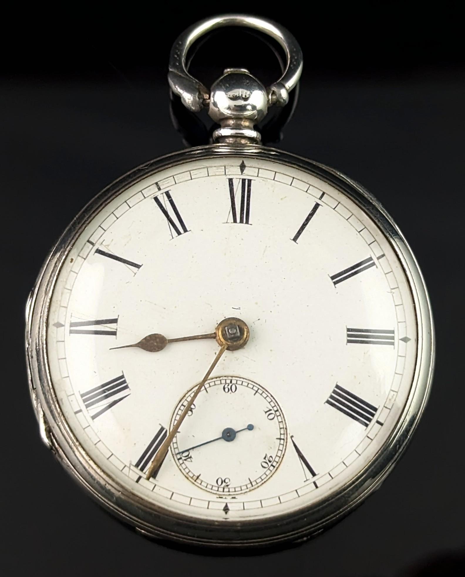 A handsome antique, Victorian era sterling silver pocket watch.

It has a sterling silver case with an engraved order of the garter design belt to the reverse, blank central cartouche so could be personalised if desired.

It has a white enamel dial