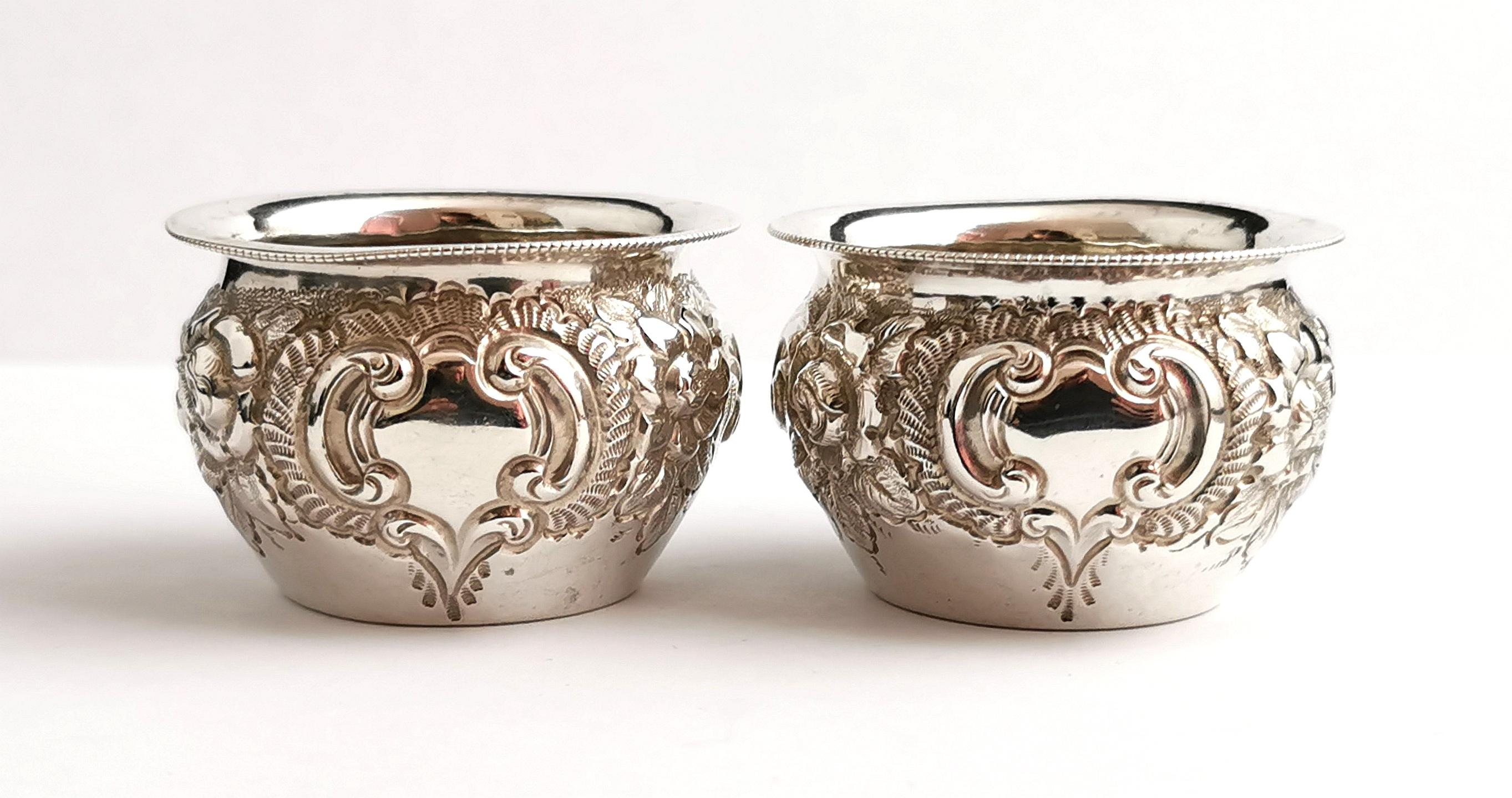 A beautiful and decorative pair of antique, Victorian era sterling silver salts.

They have a pretty repousse floral design each with a blank cartouche to the front which could be monogrammed if desired.

No liners or spoons.

They are fully
