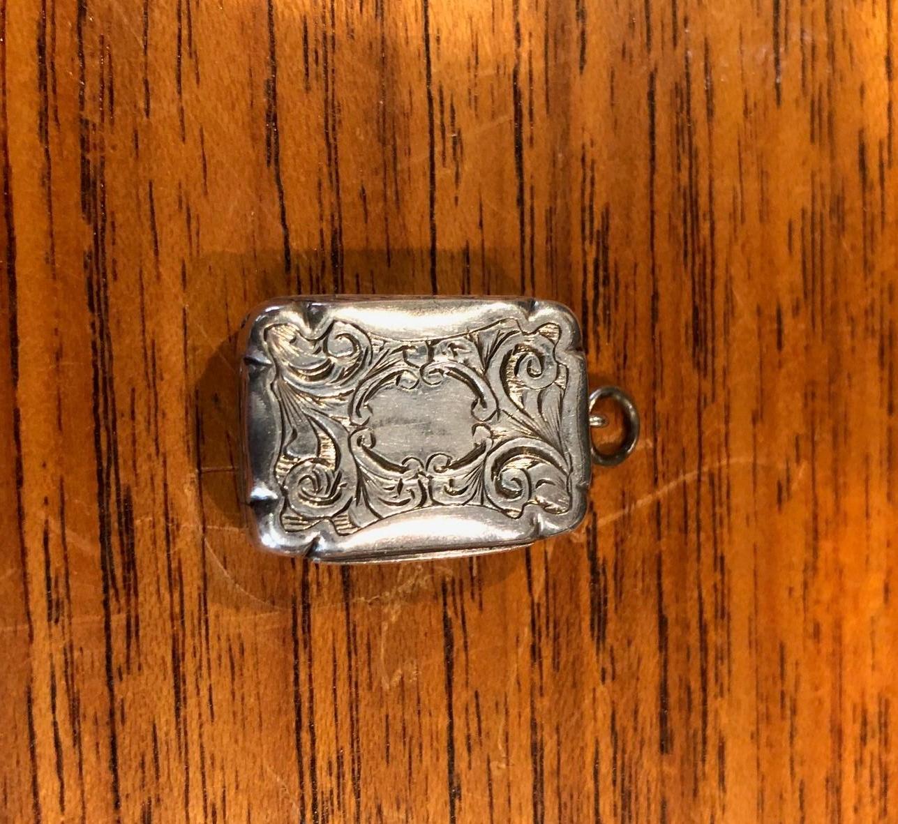 A fine quality Victorian sterling silver miniature vinaigrette by Hilliard & Thomason of Birmingham, England, circa 1963. The piece is of rectangular form with richly engraved top and bottom. The gold gilt interior with finely pierced foliate scroll