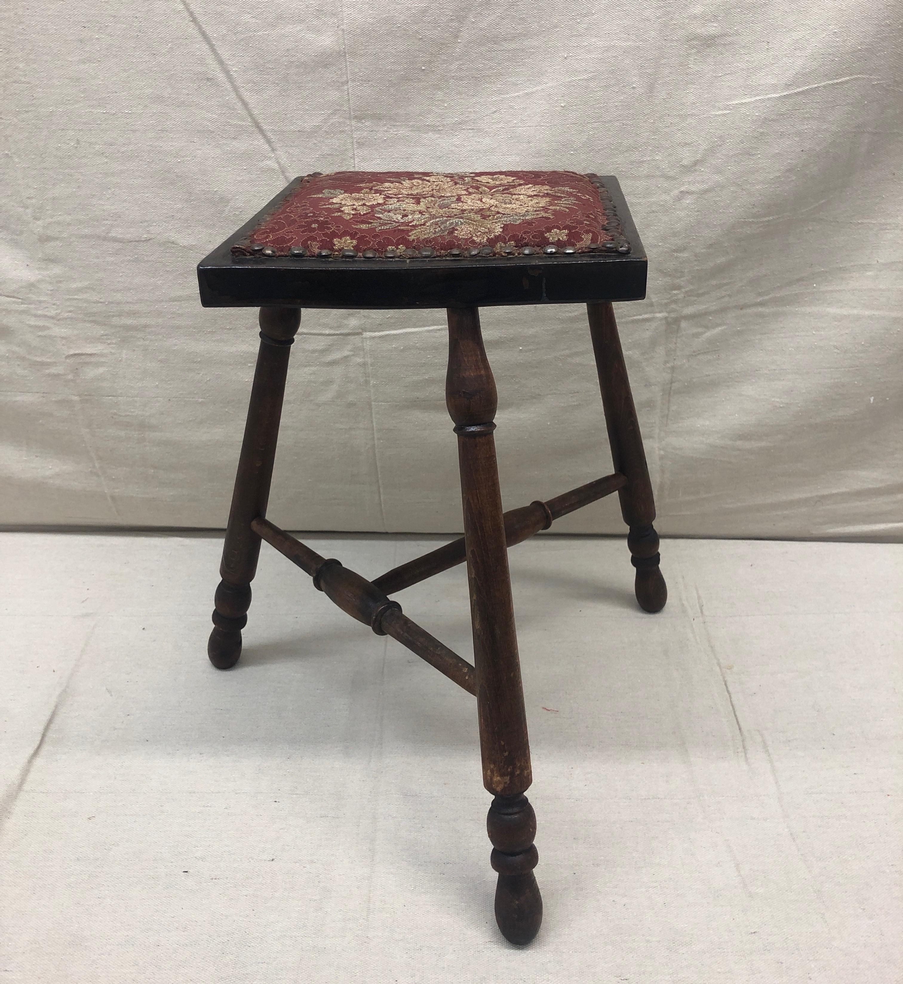 Antique Victorian stool with tapestry style seat.
Unusual top and stretchers.
Three leg stool. Rustic nailheads around the seat.
Size: 16” W x 16” D x 17” H.