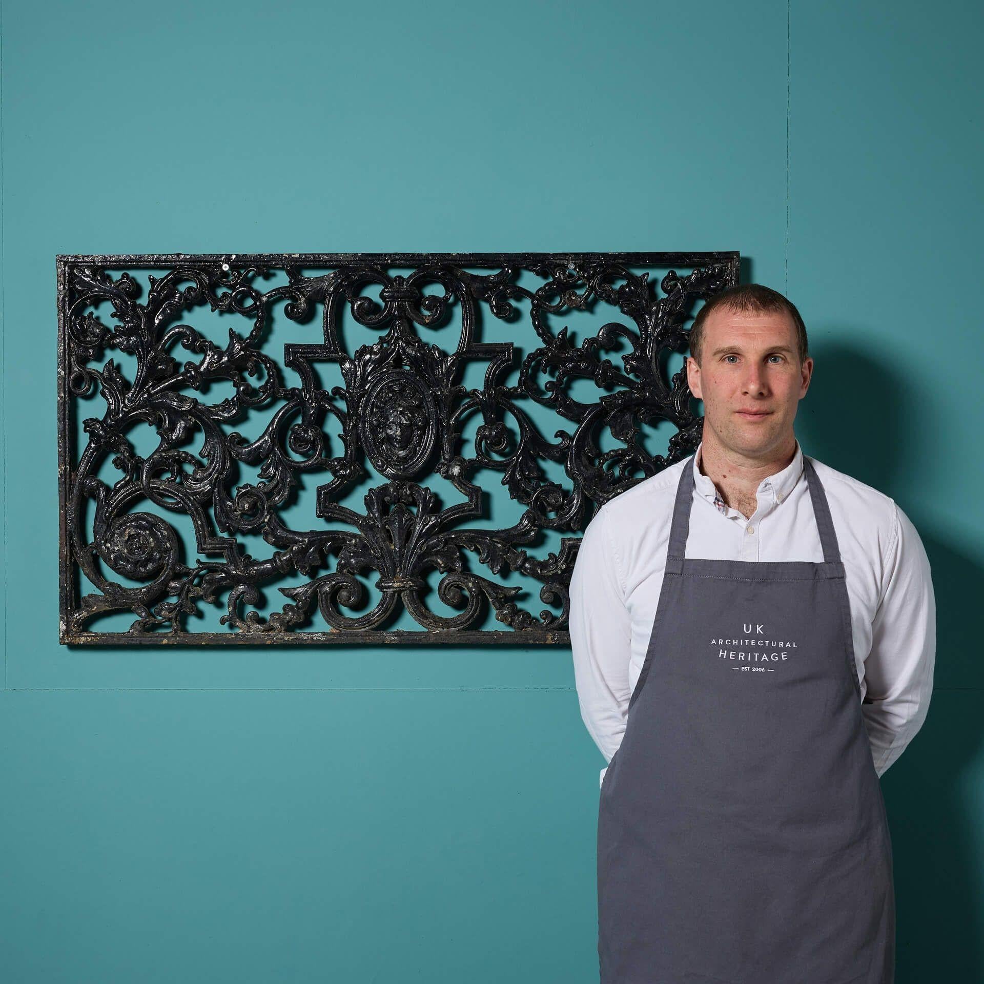 Panneau décoratif antique en métal moulé de style victorien représentant un feuillage en volutes et un masque au centre, avec une finition noire légèrement altérée par les intempéries.

Une telle antiquité décorative est digne d'être exposée dans