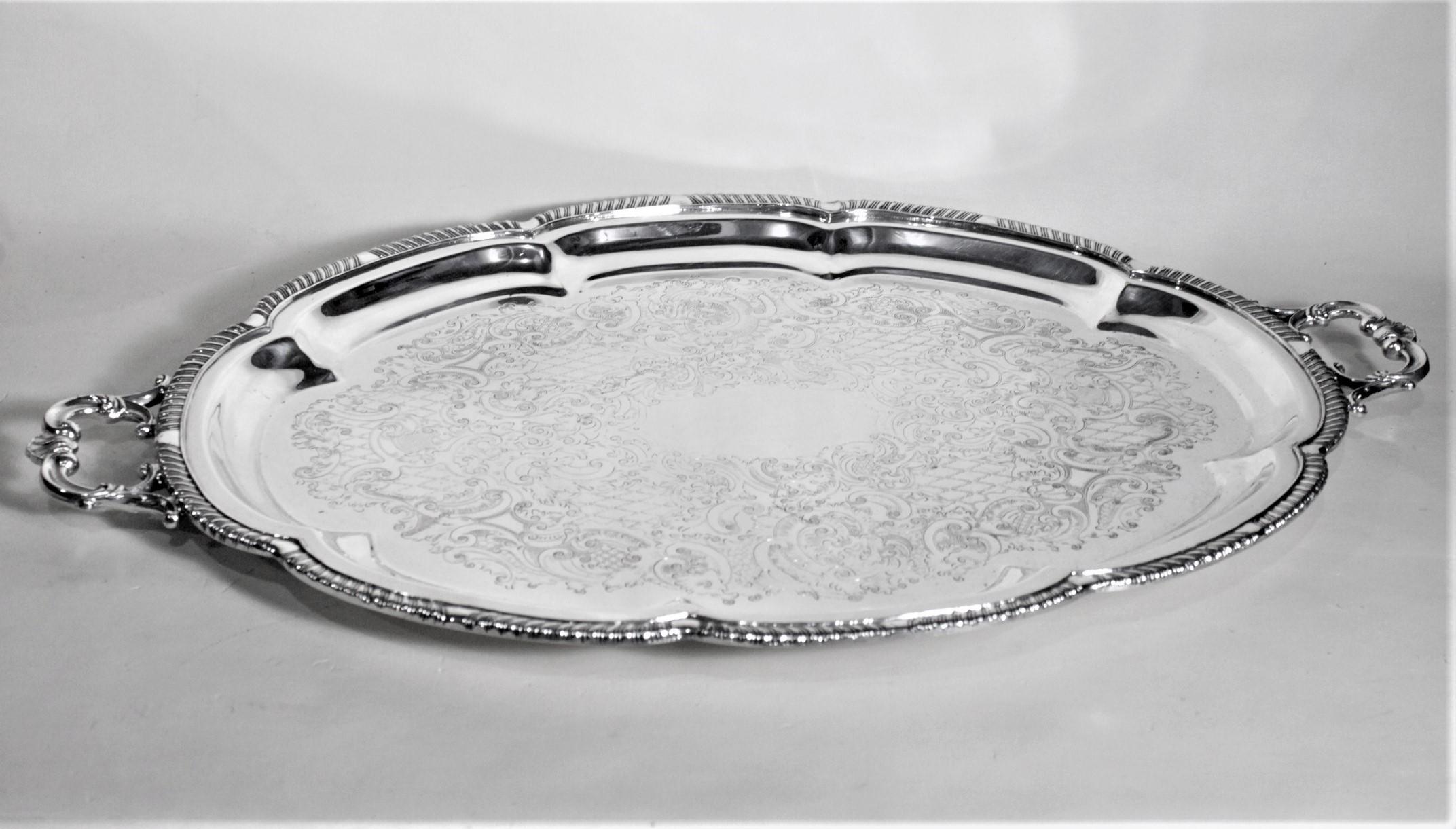 This antique styled silver plated serving tray was made by the Roger's Bros. of the United States in approximately 1950 in a Victorian style. The tray is silver plated copper in construction and has a scalloped tiered surround with a rope motif
