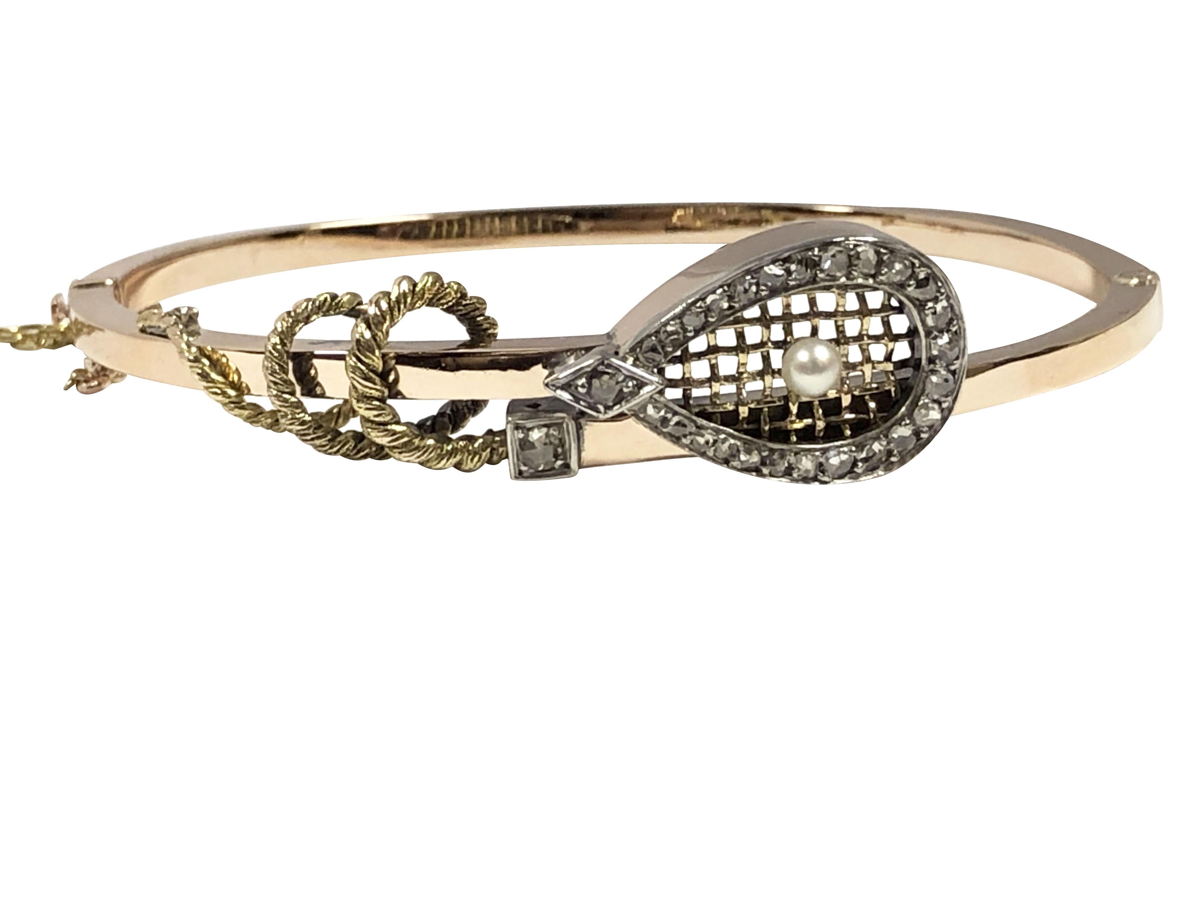 Circa 1900 - 1910 Late Victorian Bangle Bracelet in the form of a Tennis Raquet, the 14k Yellow Gold bracelet measures 1/8 inch wide with the top measuring 1 1/2 inches, the top of the Raquet is Silver and is set with Rose cut Diamonds with a Pearl,