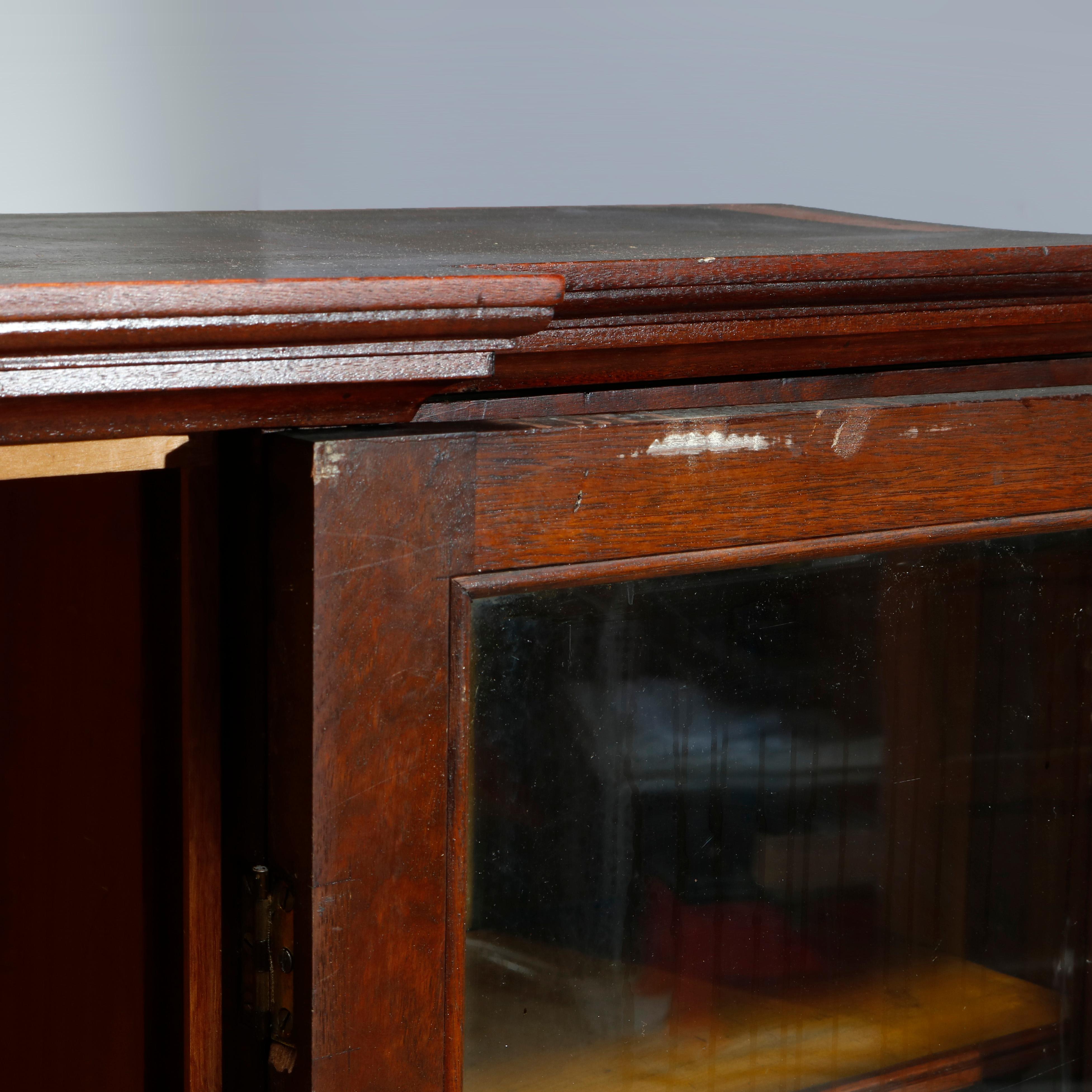 An antique Victorian step-back bookcase offers mahogany construction with three glass doors opening to shelved interiors and surmounting three lower drawers, c1900

Measures: 62