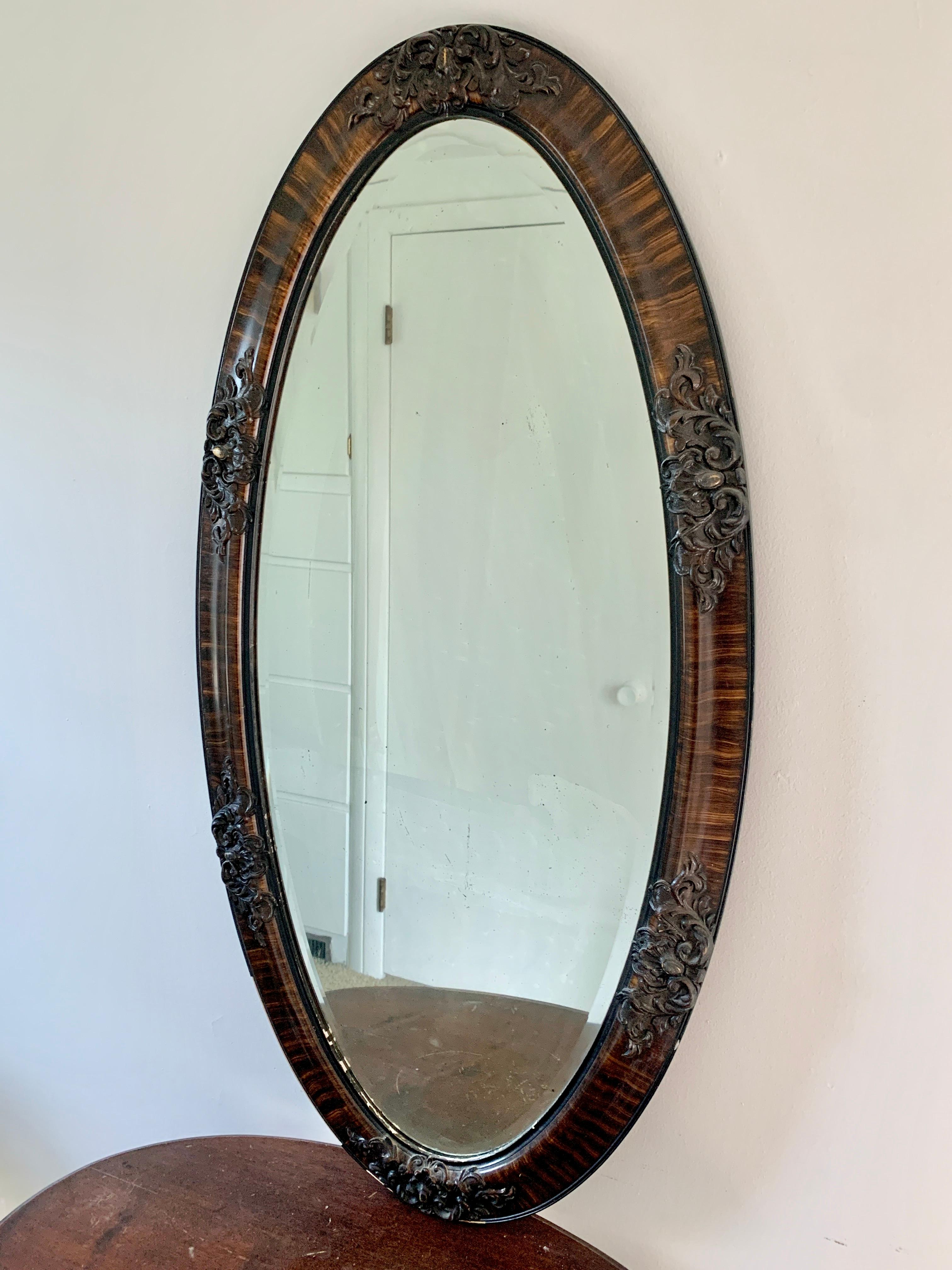A gorgeous antique Victorian oval wall mirror with carved details

USA, circa Late 19th century

Carved tiger oak frame, with gold gilt details, and beveled antique mirror

Measures: 23