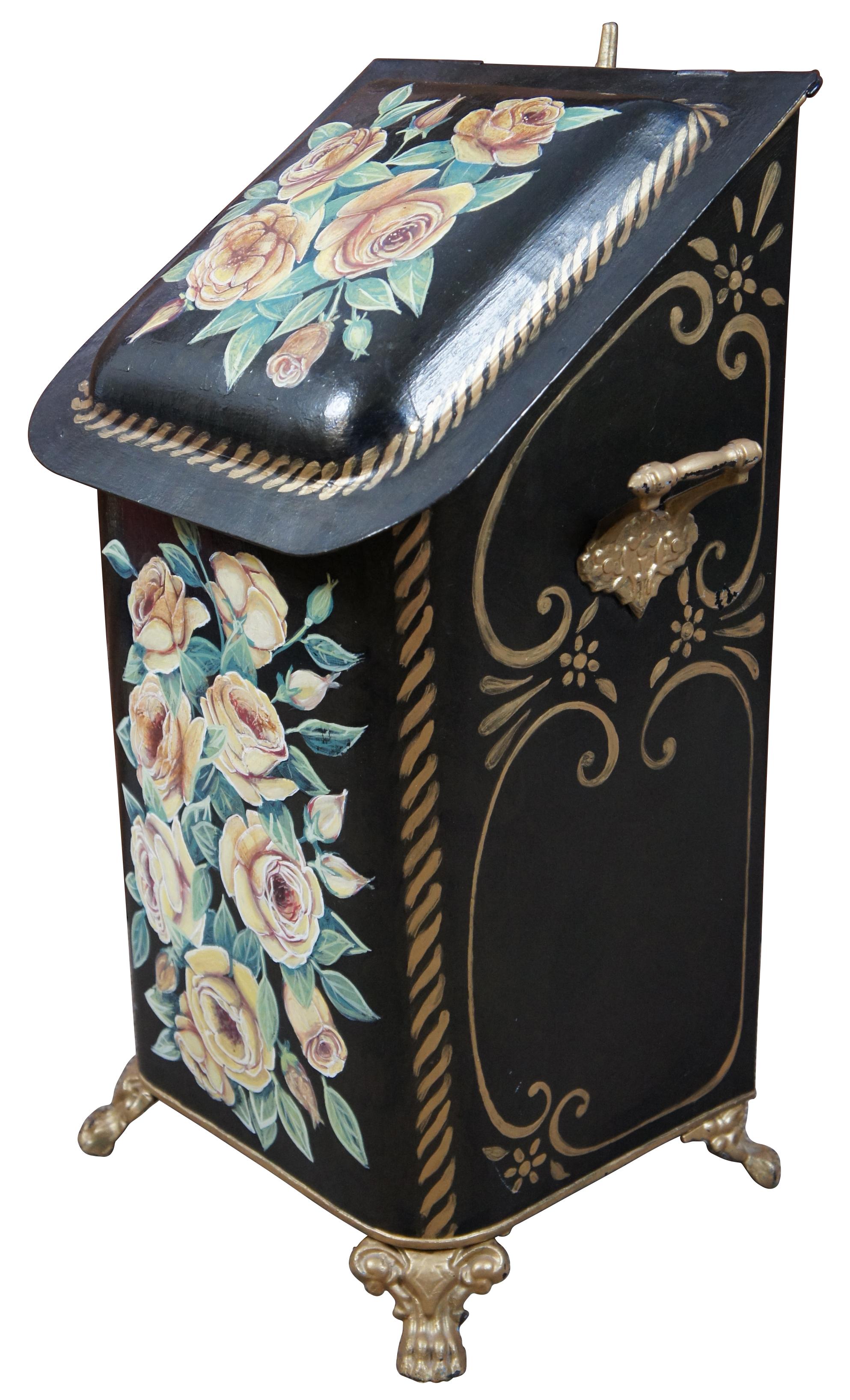 Antique Victorian toleware metal coal bin or heartherware hod with lid, painted floral motif in black with yellow and pink roses, accented with gilded feet, handles, and rear hook for a shovel.
 
