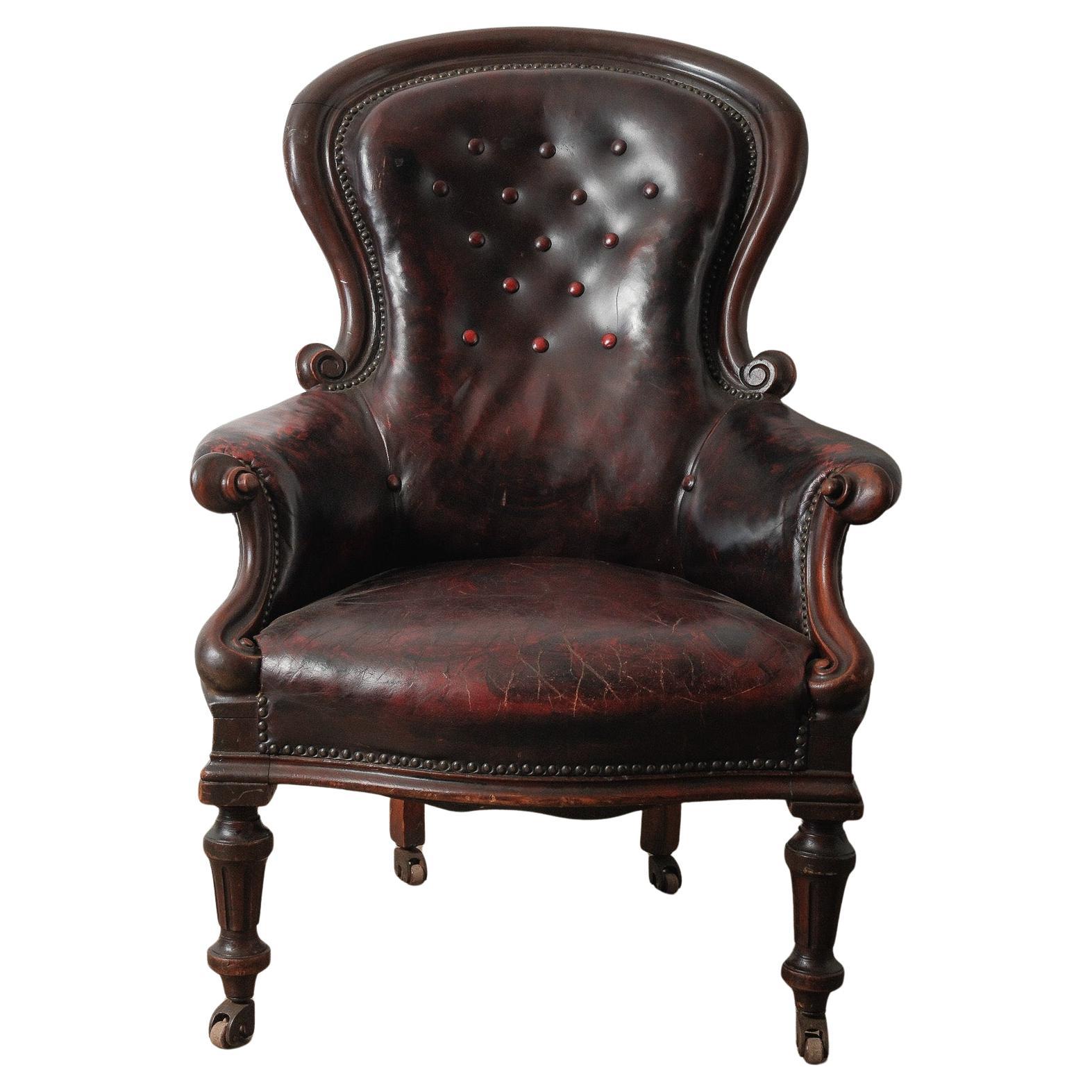 Fauteuil victorien ancien en cuir capitonné sur roulettes