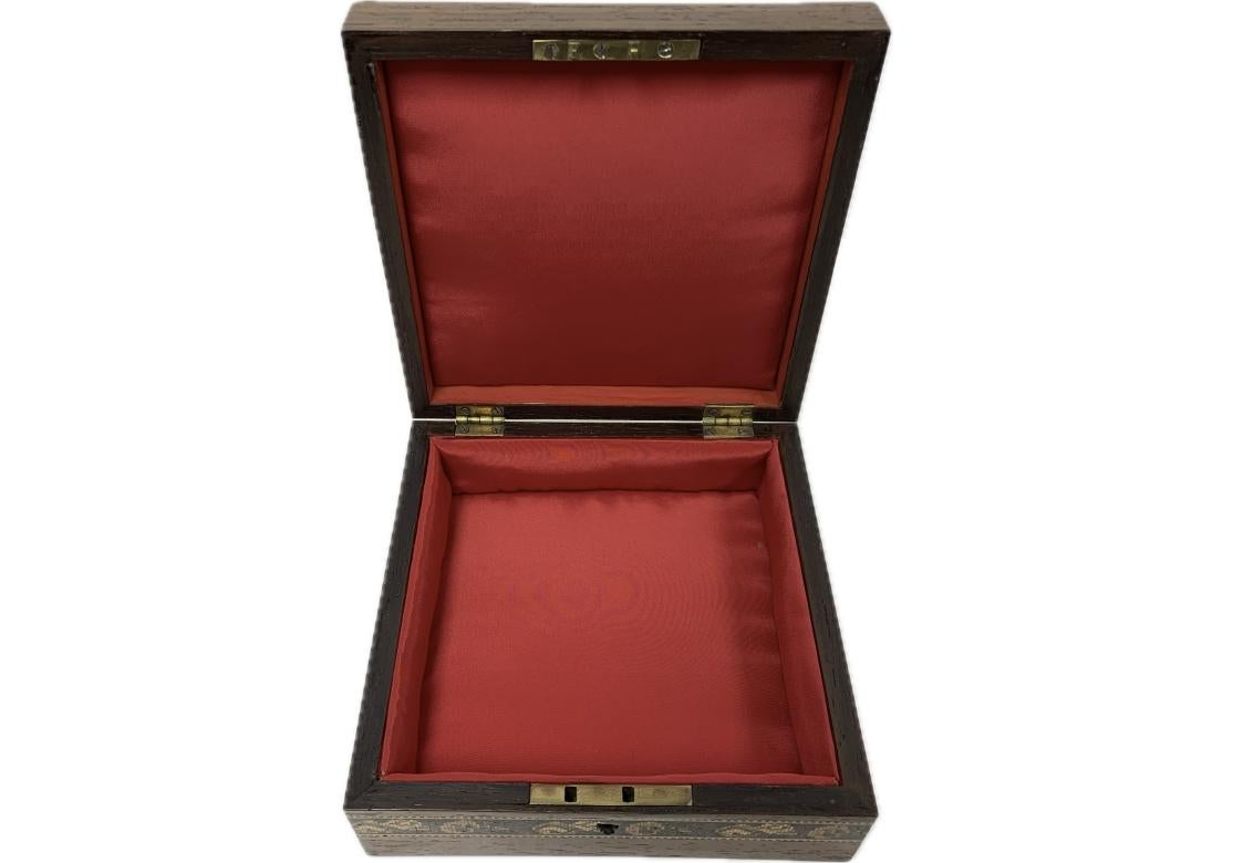 Caja de pañuelos victoriana de madera de palisandro de Tunbridge Ware con tapa decorada con un grupo floral en mosaico en el centro y un borde floral, que se abre para revelar un interior forrado de seda roja. 

Dimensiones: 6