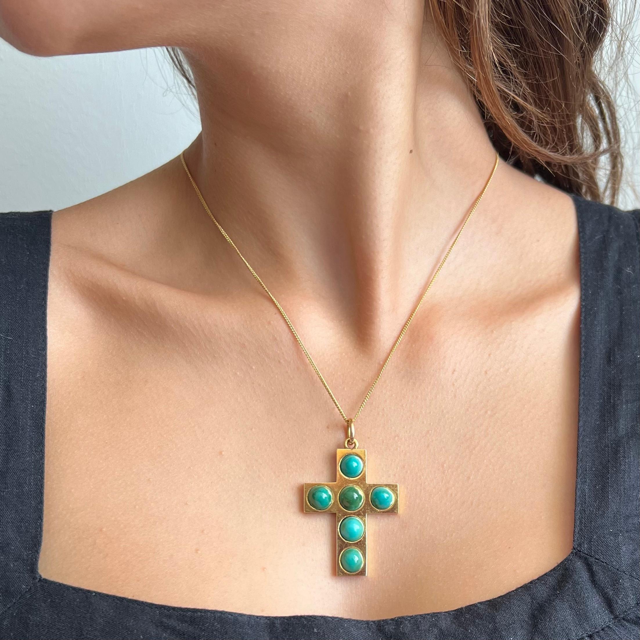 An antique Victorian 14 karat yellow gold cross pendant created with turquoise cabochon stones. This lovely antique cross is beautifully decorated with an array of blue-green turquoise cabochons across the front. The turquoise cabochon stones are