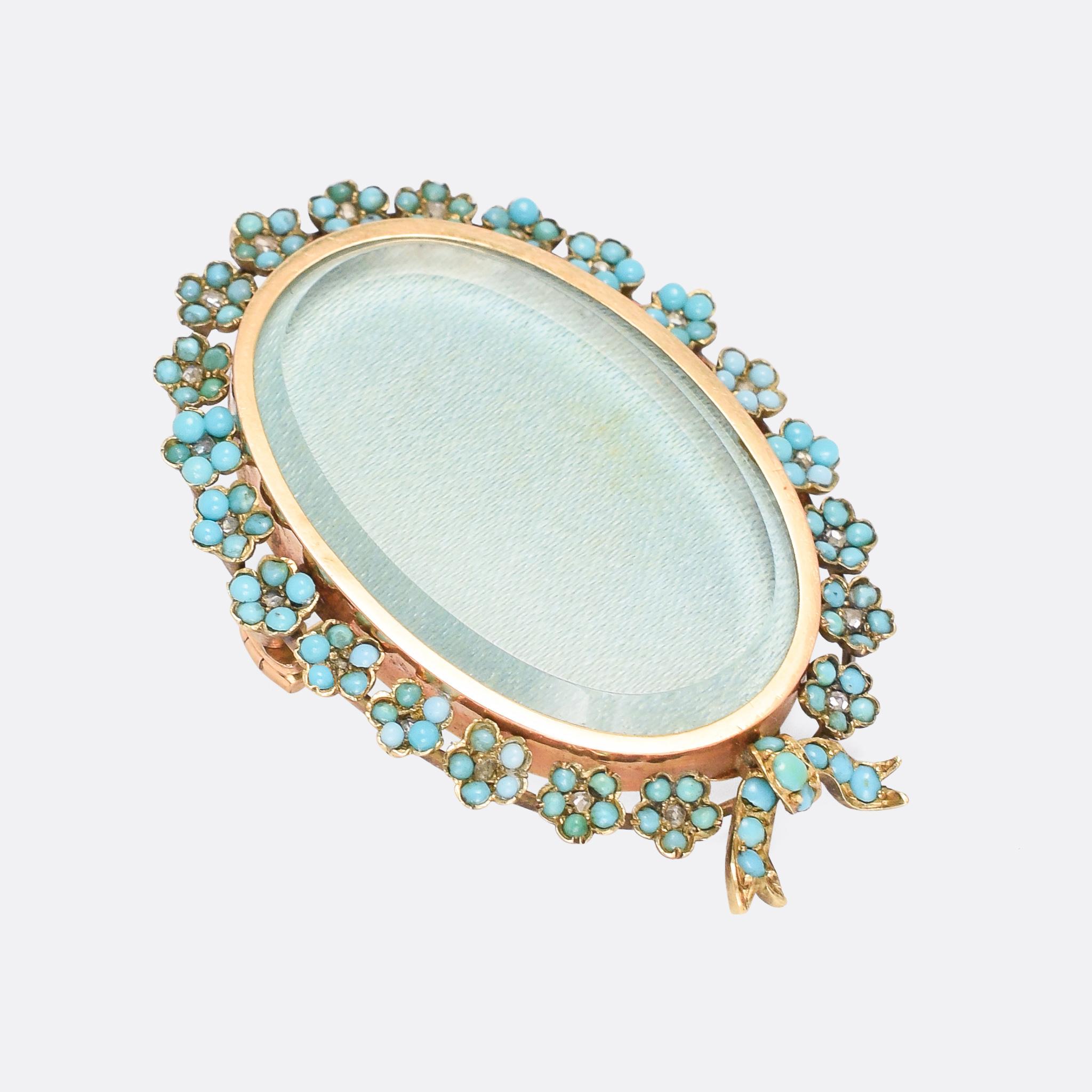 A beautiful antique locket, with fittings for wear either as a brooch or a pendant. The bevelled glass front is accessed from the back, and bordered by intricately worked forget-me-not flowers – each one set with five turquoise cabochon petals and a