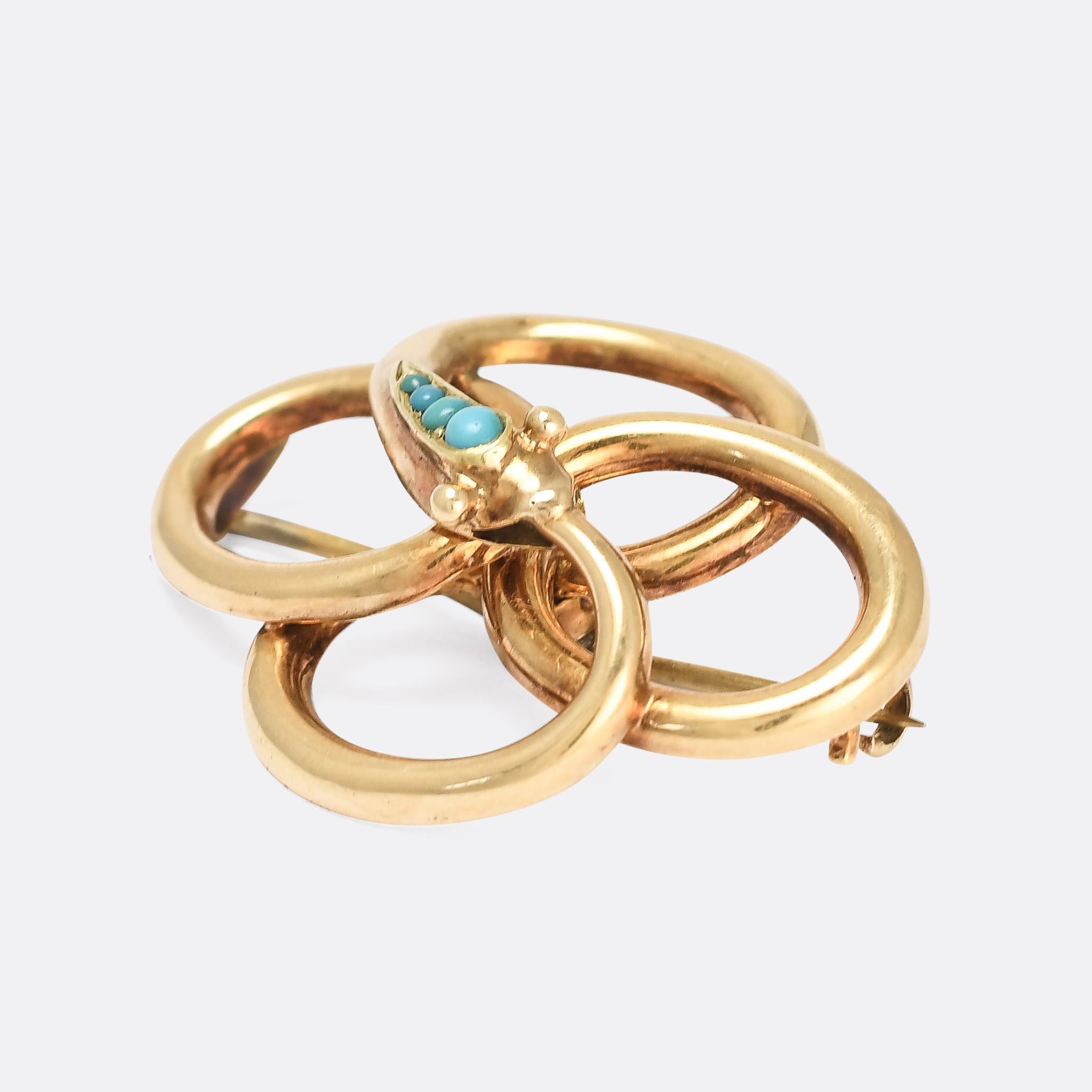 A gorgeous antique serpent brooch in 15 karat gold. It dates from the mid Victorian period, circa 1860, with a graduated row of turquoise cabochons and a cartoonish head/face. The body coils around itself, formed into quatrefoil, and ends with the