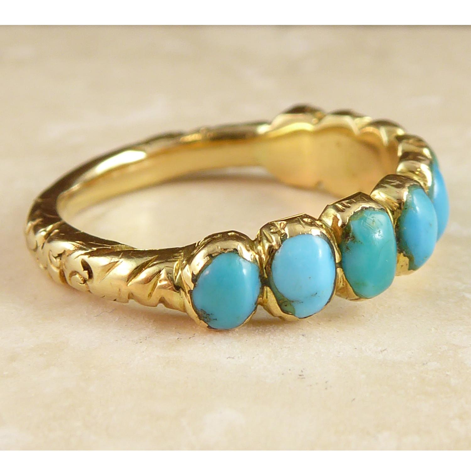 An antique Victorian wedding band set with a row of nine cabochon cut turquoise gemstone in rub-over gold mounts.  The style of the setting gives a scalloped edge to both sides of the turquoise set section.  The turquoise decline in size from the