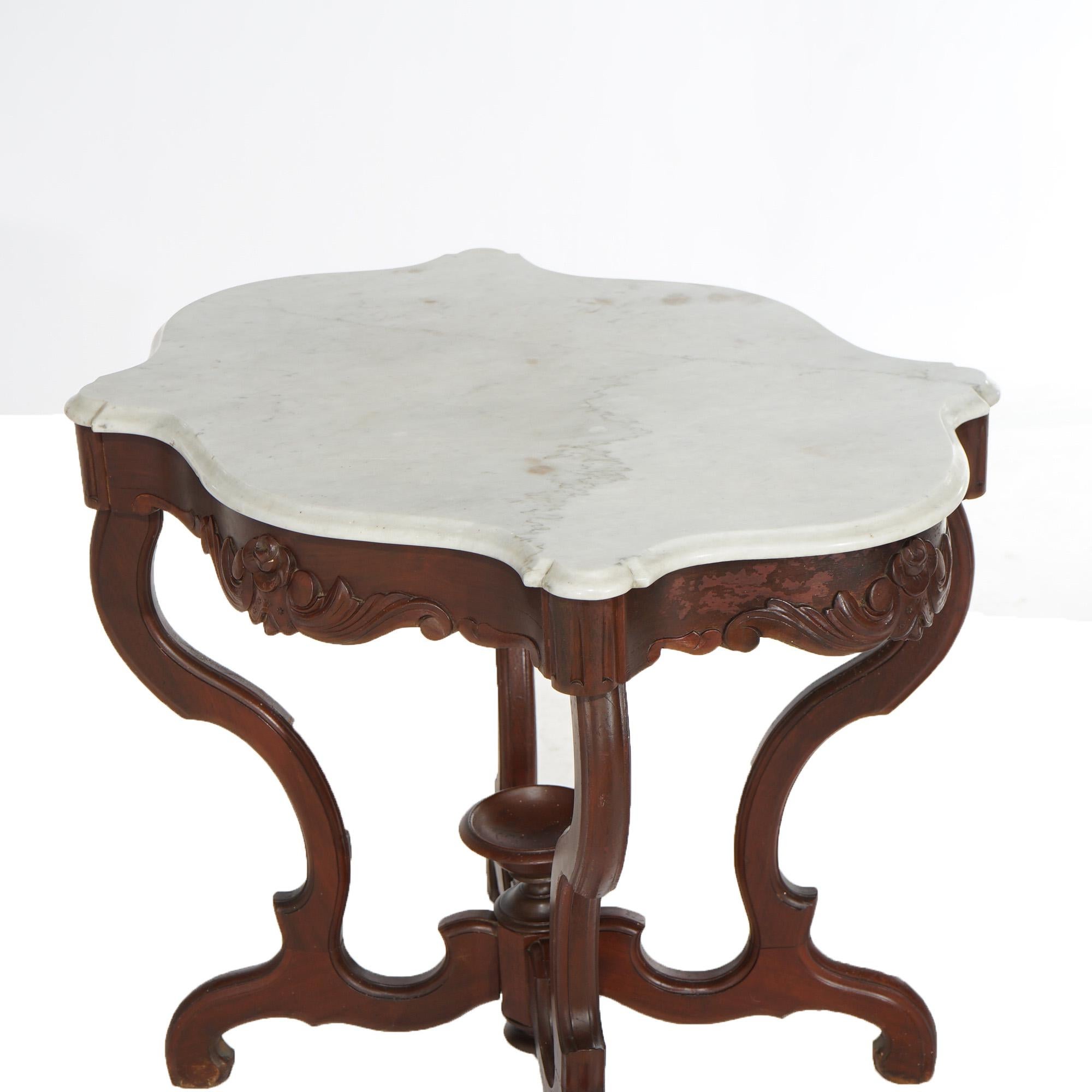 An antique Victorian parlor table offers shaped and beveled marble turtle top over walnut base having carved floral elements, central chalice form finial and scroll form legs, c1890

Measures- 28.5''H x 33.75''W x 25''D