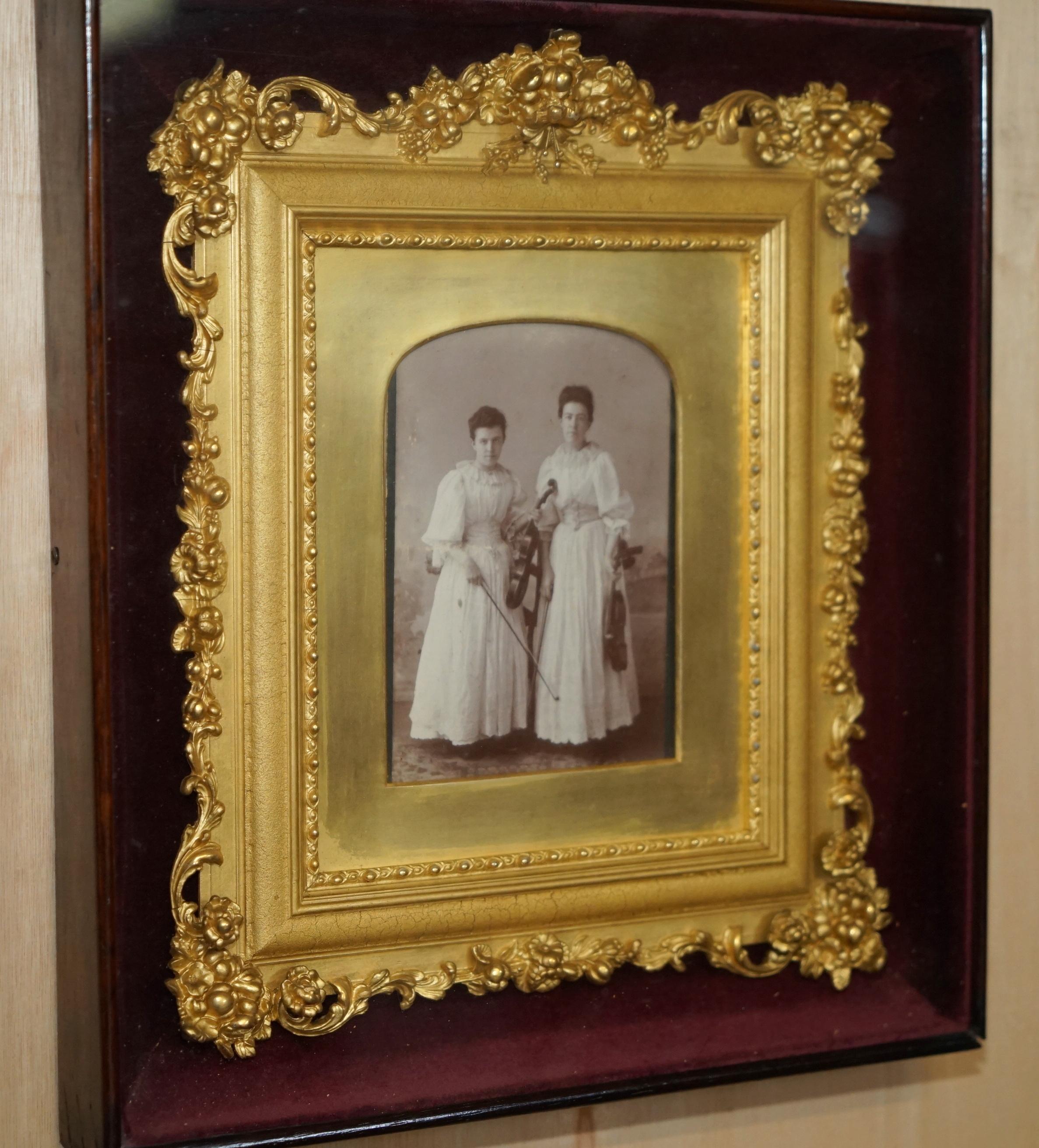 Royal House Antiques

Royal House Antiques is delighted to offer for sale this lovely, one of a kind Victorian photo of two young violinist girls in a period gilt frame which has been cased and protected in a secondary case with the original maker