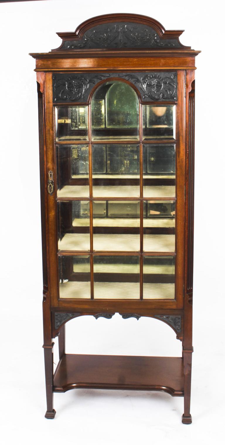 This is an exquisite antique late Victorian mahogany upright display cabinet C1890 in date.
 
 The cabinet features a rectangular top with carved gallery back decorated with ribbons and foliate cresting above a single astragal glazed door which