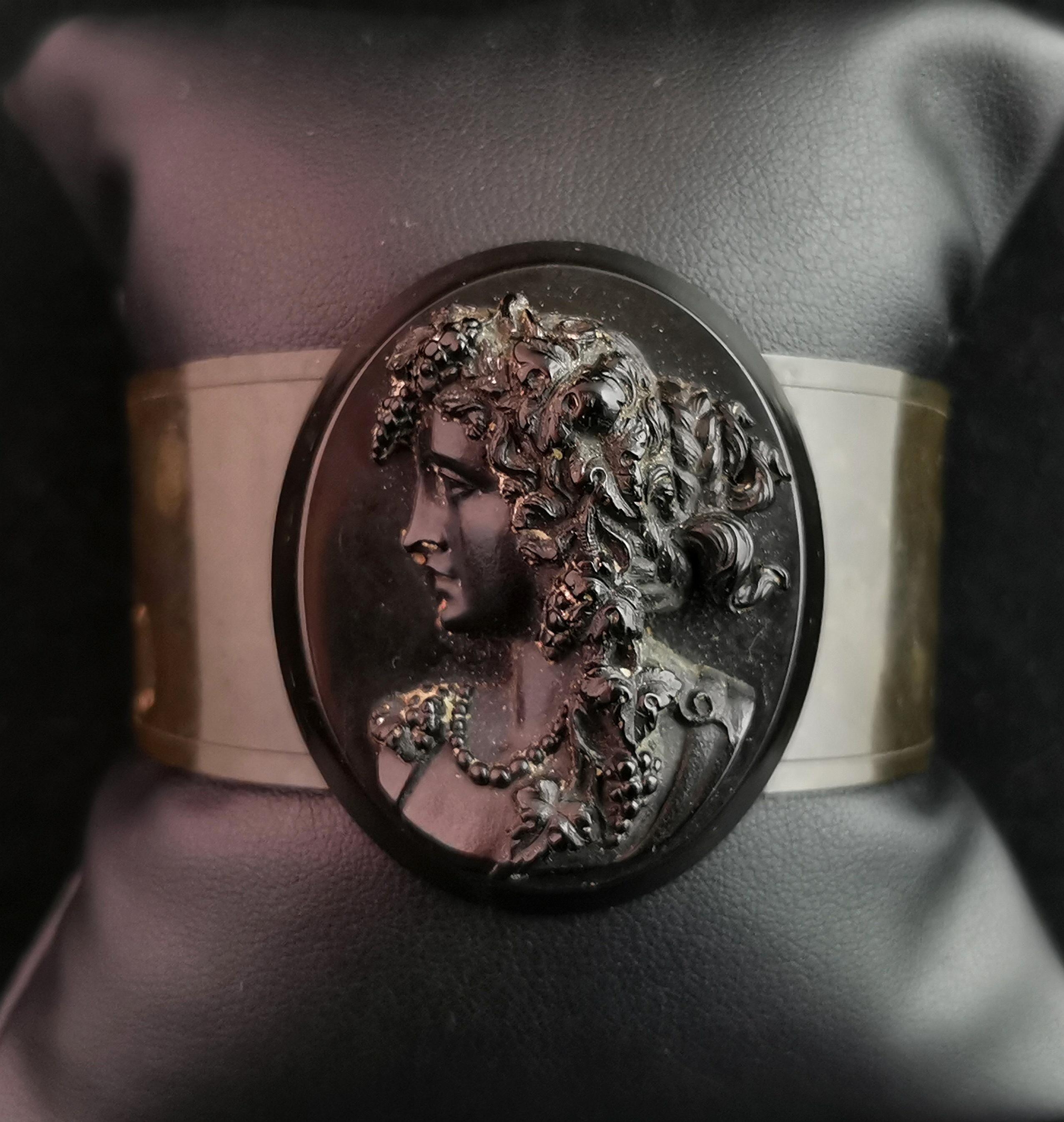A beautiful antique Victorian era, Vulcanite and Jet cameo bangle.

The bangle is made from vulcanite and is an open ended bangle designed to slip over the wrist.

The front is adorned with a carved jet cameo of a maiden with flowing hair and a