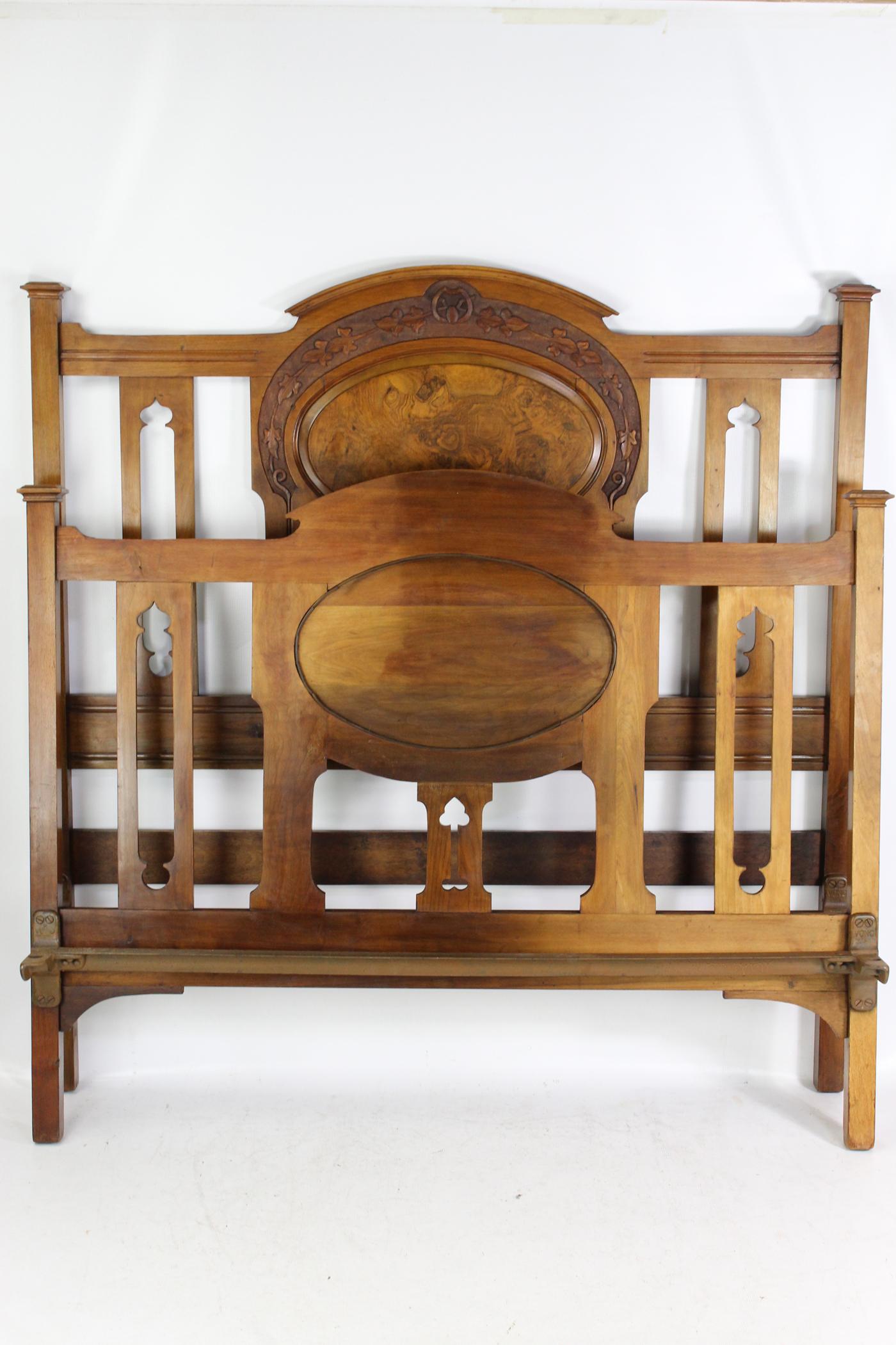 A charming antique Victorian Arts & Crafts carved walnut double bed dating from circa 1890. The headboard and footboard in a richly figured walnut frame with attractive foliate carved top rail and central burr walnut panel above vertical slats with
