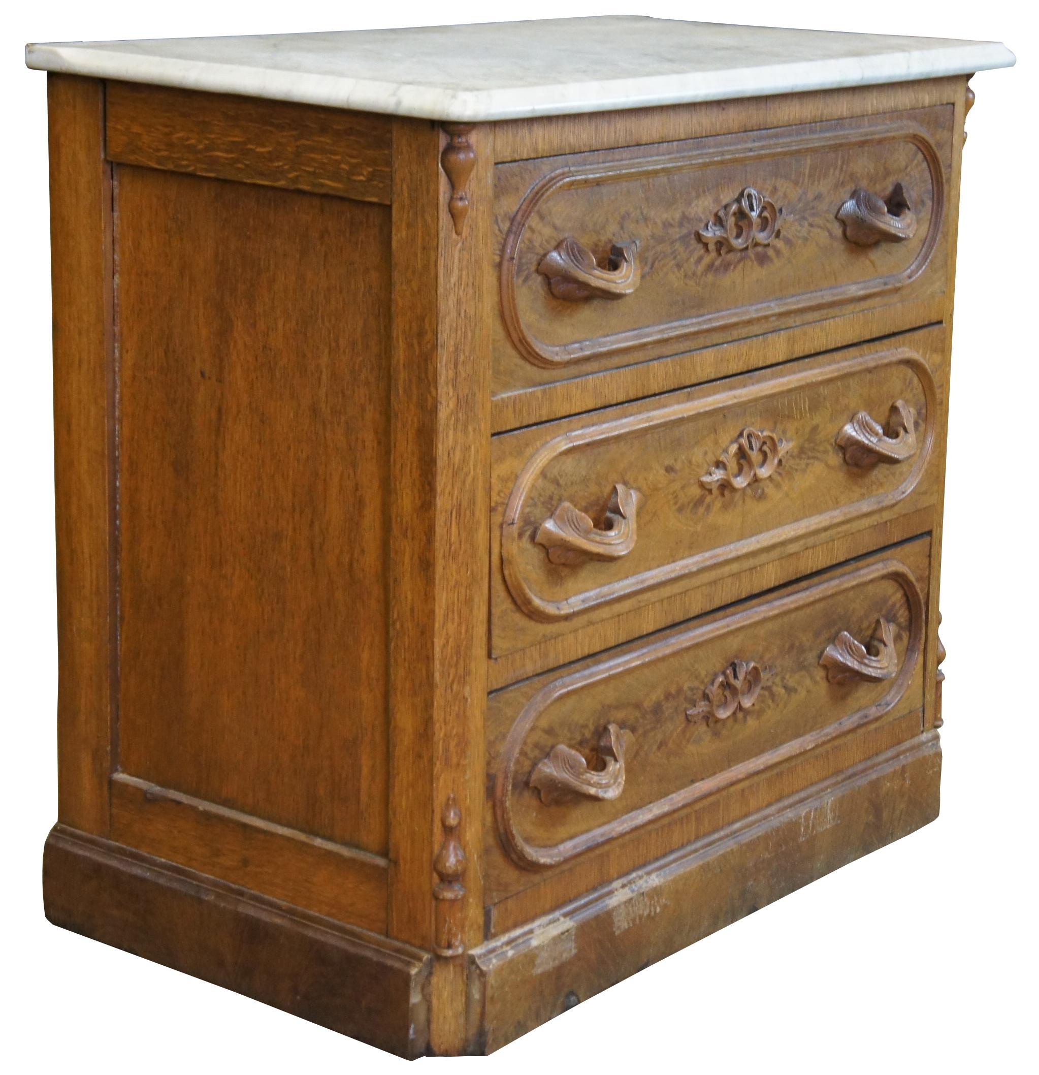 Antique Victorian marble top dresser. Made from quartersawn oak with walnut burled veneer front. Each drawer features an ornately carved key hole and hand carved drawer pulls centered between an oval molding. Includes marble top, spindled corners