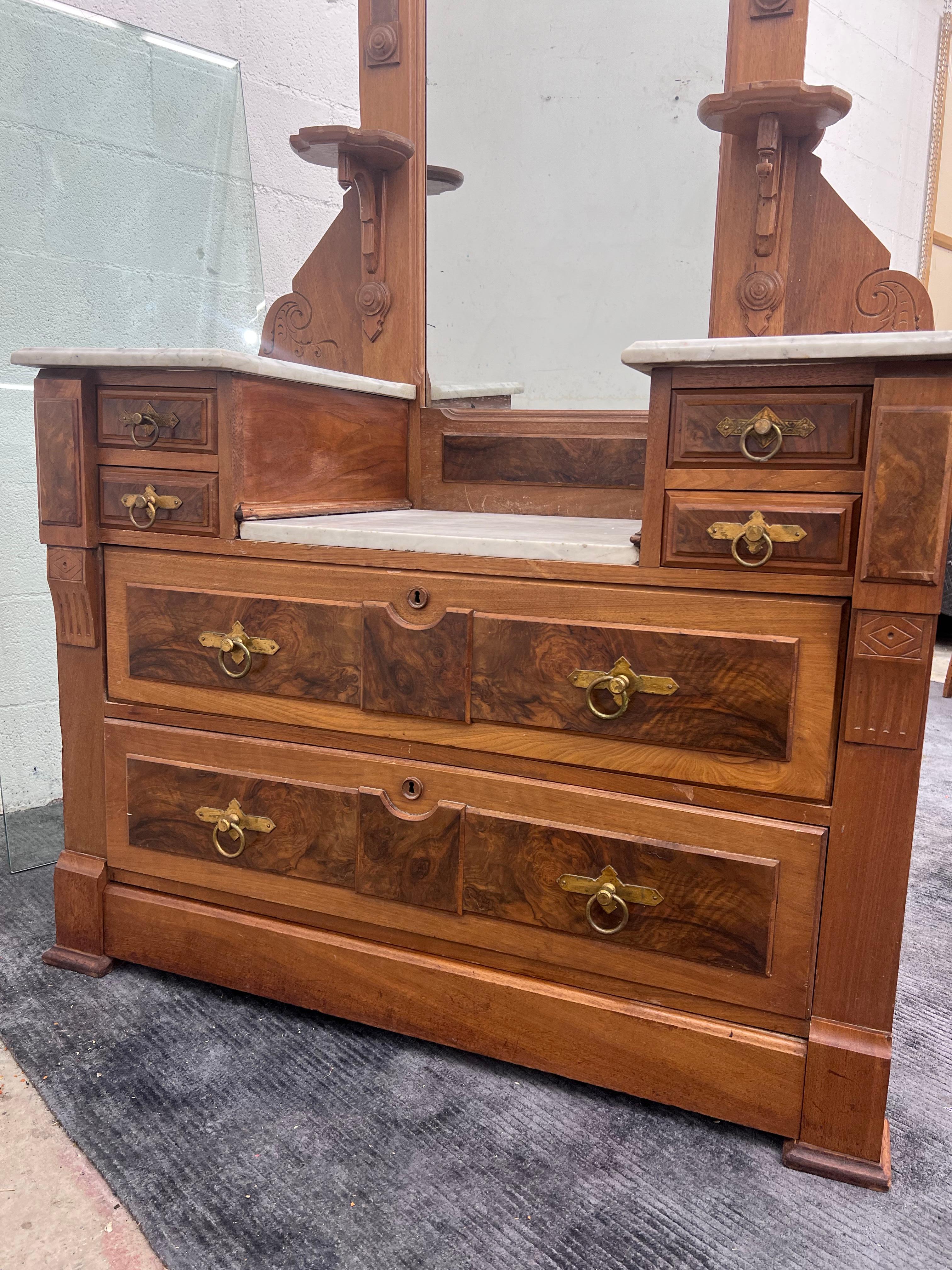 19th century Eastlake two tiered marble dresser with tall Mirror. Constructed out of solid walnut with burled drawer fronts and hand carved details throughout. 
The dresser has solid brass handles and dovetailed joints. The mirror can be