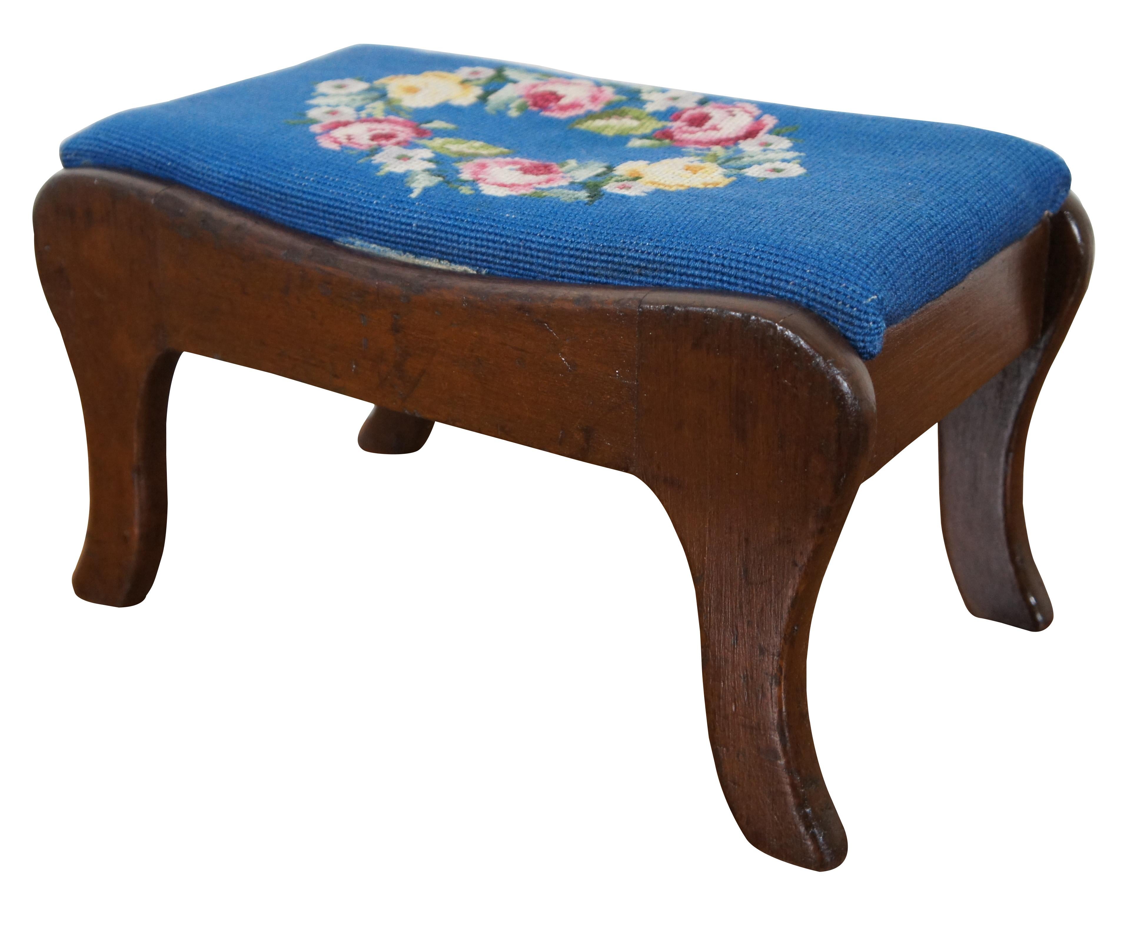 Antique Victorian walnut footstool with hand stitched blue needlepoint cushion showing a wreath of roses and morning glories on a blue ground.