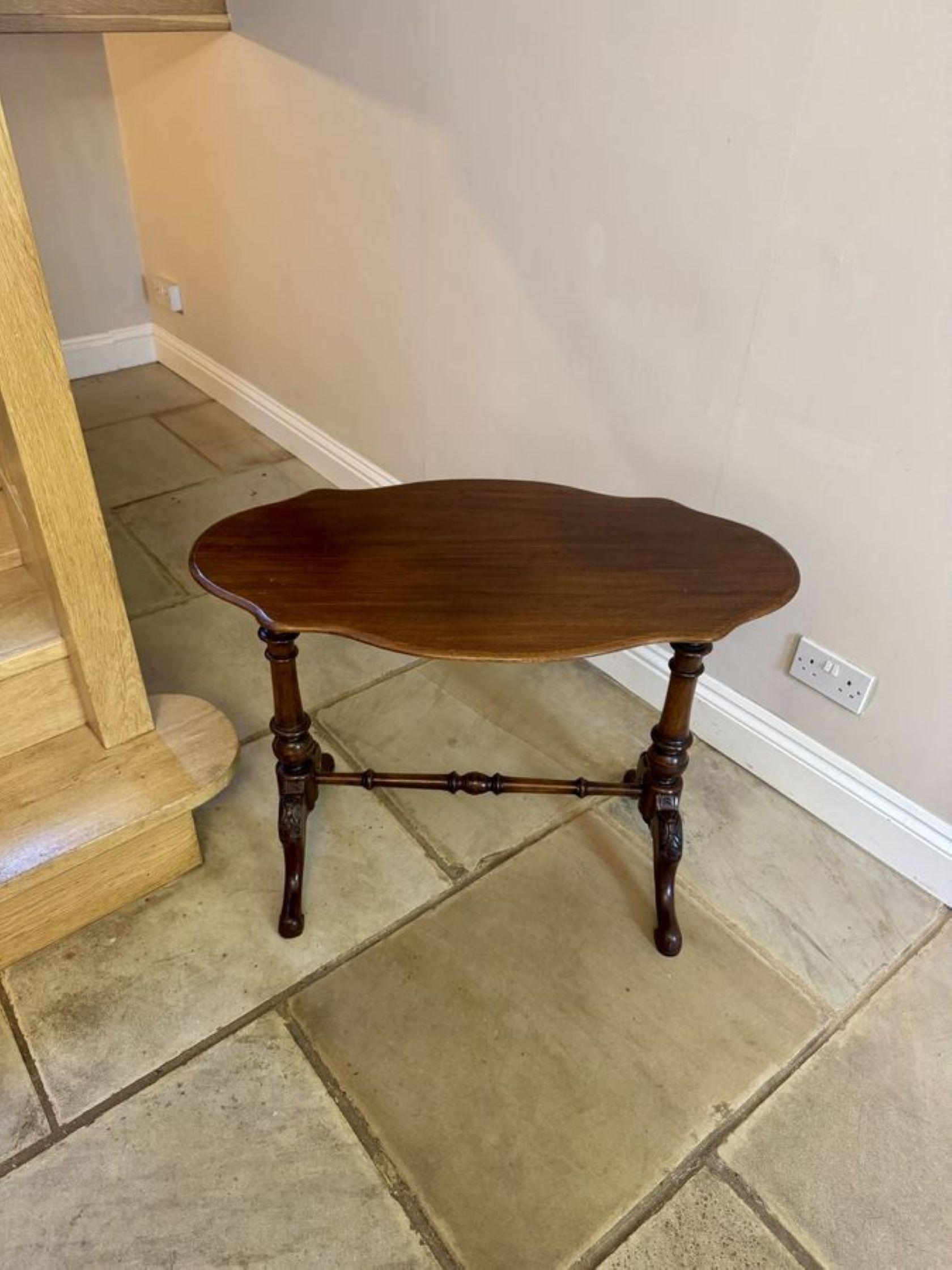 Antique Victorian walnut lamp table, having a solid walnut serpentine shaped top with a thumb moulded edge supported turned columns, standing on shaped carved cabriole legs with scroll feet united by a turned stretcher. 

D. 1860