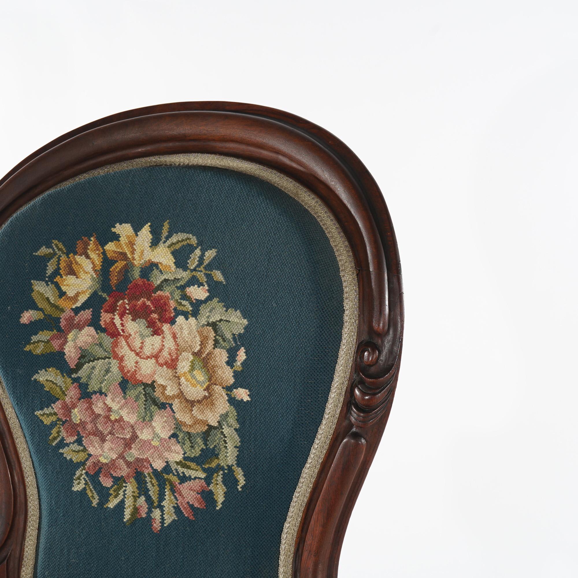 An antique Victorian ladies parlor chair offers carved walnut frame with shaped back having floral needlepoint upholstery, matching seat and covered arms; raised on cabriole legs; c1890

Measures - 39