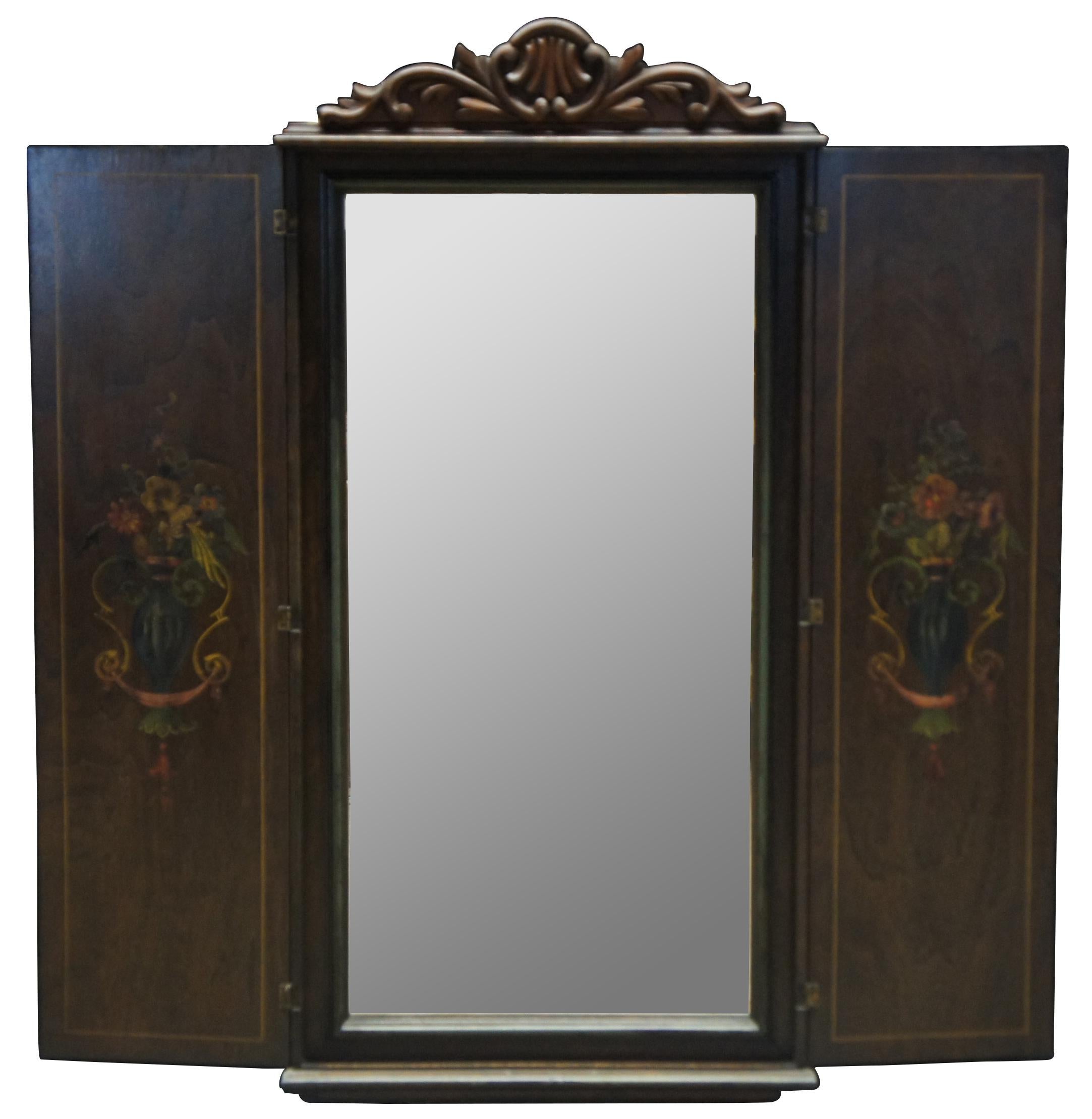 Antique wall hanging wood cabinet with stenciled floral border. The two doors open to reveal a rectangular mirror flanked by painted neoclassical vases of flowers.

Measures: 17.75” x 2.25” x 36” / Mirror - 13.5” x 27.5” / Width Open – 34.25”