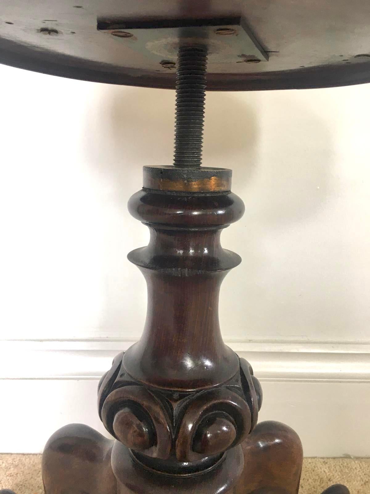 Antique Victorian walnut piano stool having a circle revolving seat newly reupholstered in a quality stylish fabric. It is raised on and elegant and carved solid walnut shaped turned column and stands on three solid walnut shaped cabriole legs with