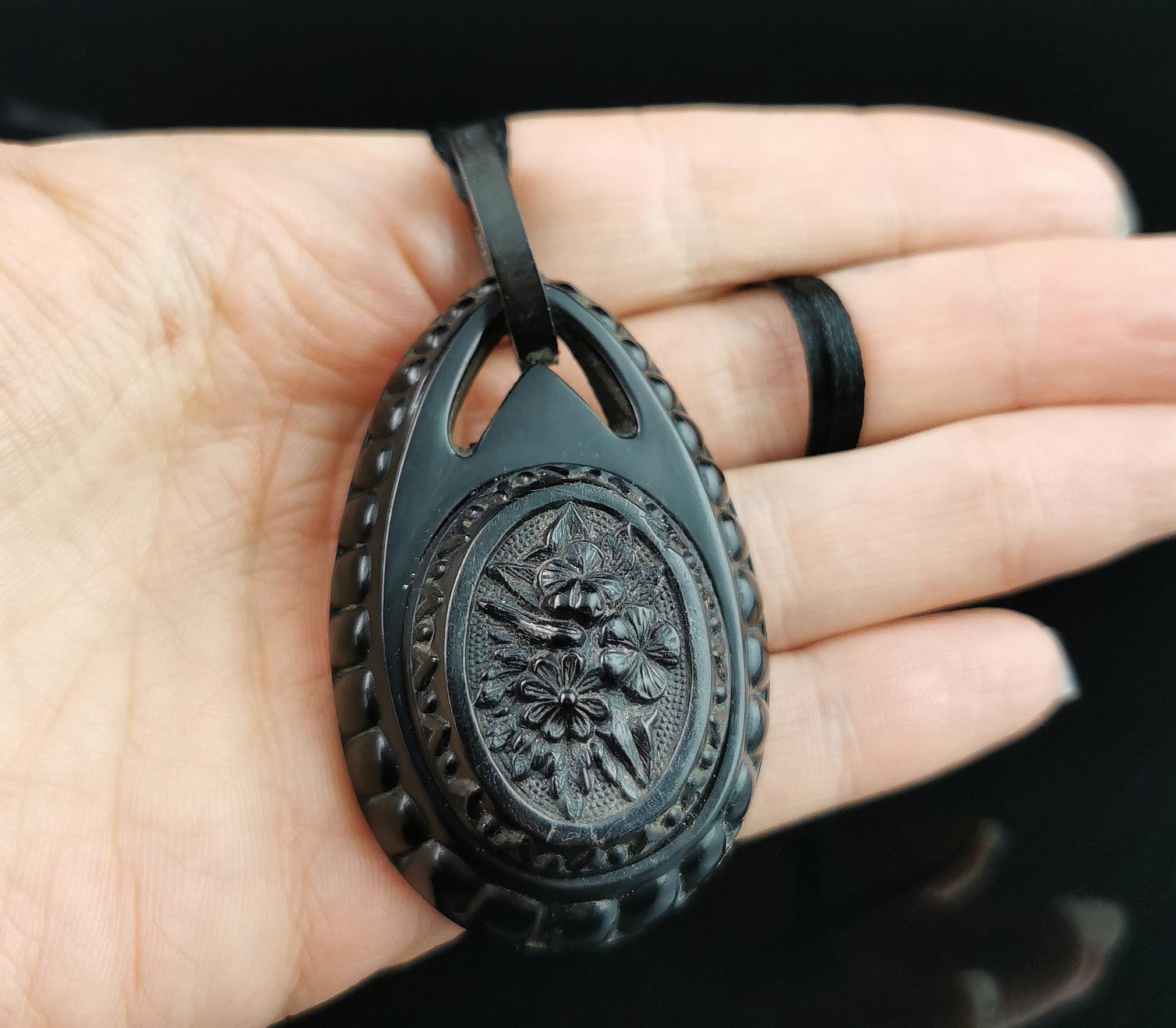 A beautiful antique Victorian era Whitby Jet pendant.

This is a large teardrop shaped pendant with a mounted plaque of carved flowers to the front and an integral jet bale.

It is highly detailed, a very pretty piece.

Whilst Whitby Jet was a