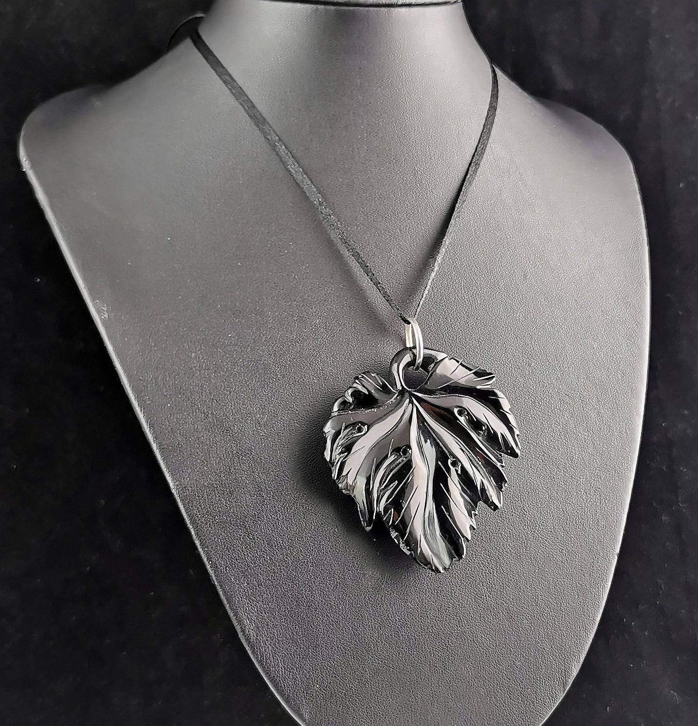 An interesting antique Victorian era carved Whitby Jet leaf pendant.

It is a large size and very nicely carved, it looks like a vine leaf, it's a conversion piece made from another piece of jewellery or possibly a belt.

It has a large silver