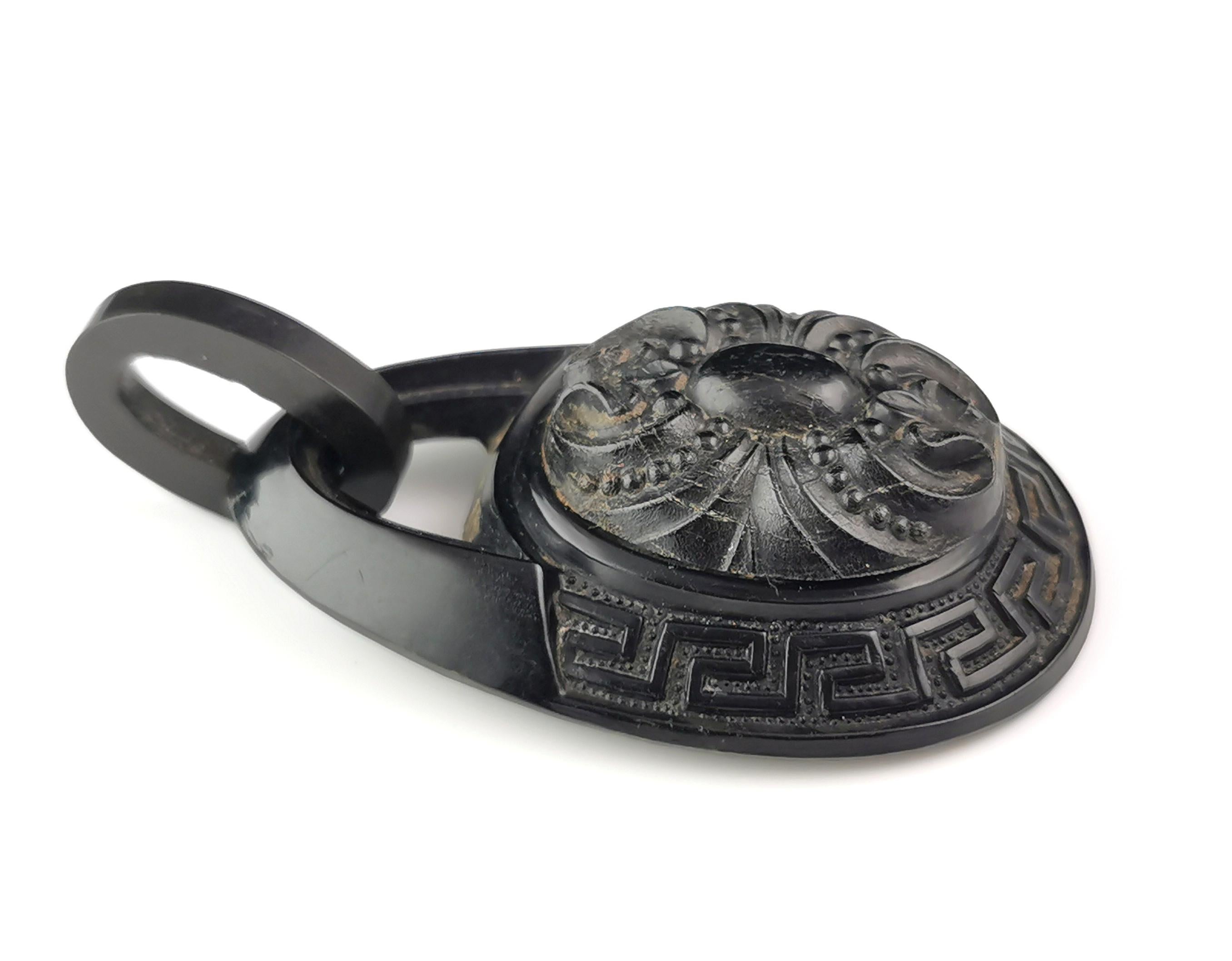 A beautiful antique Victorian era Whitby Jet pendant.

This is a large teardrop shaped pendant with a mounted plaque of carved fleur-de-lis to the front and an integral jet bale.

It has a gorgeous Greek key design around the outer rim.

It is