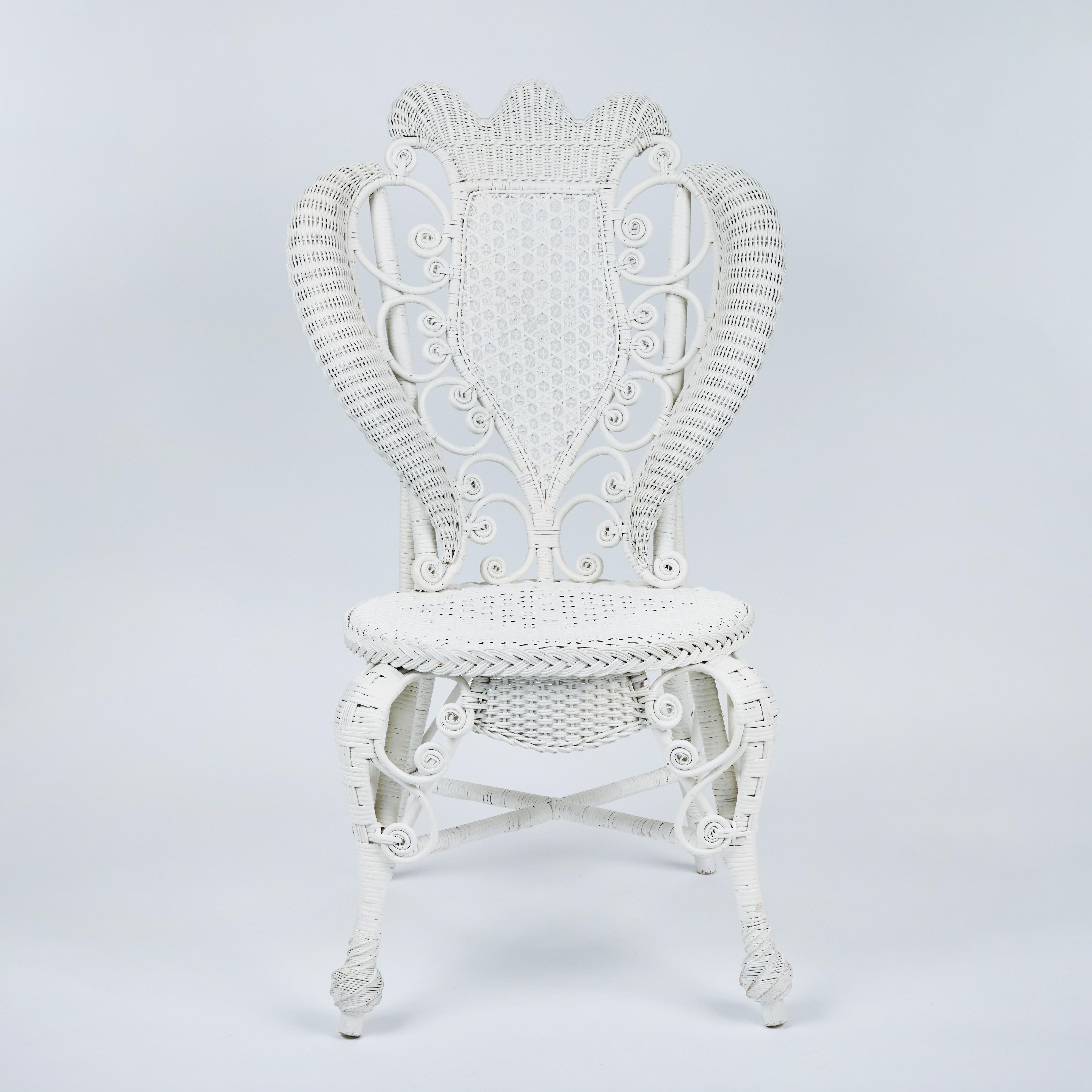 This special antique Victorian white wicker chair is possibly from the end of the 19th century. It has an elaborate designed panel through the back and is accented with curlicues throughout. This overall decorative design is very shapely and sensual