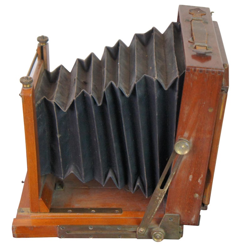 Antique Victorian folding wood camera featuring brass hardware, accordion bellow, and plates.